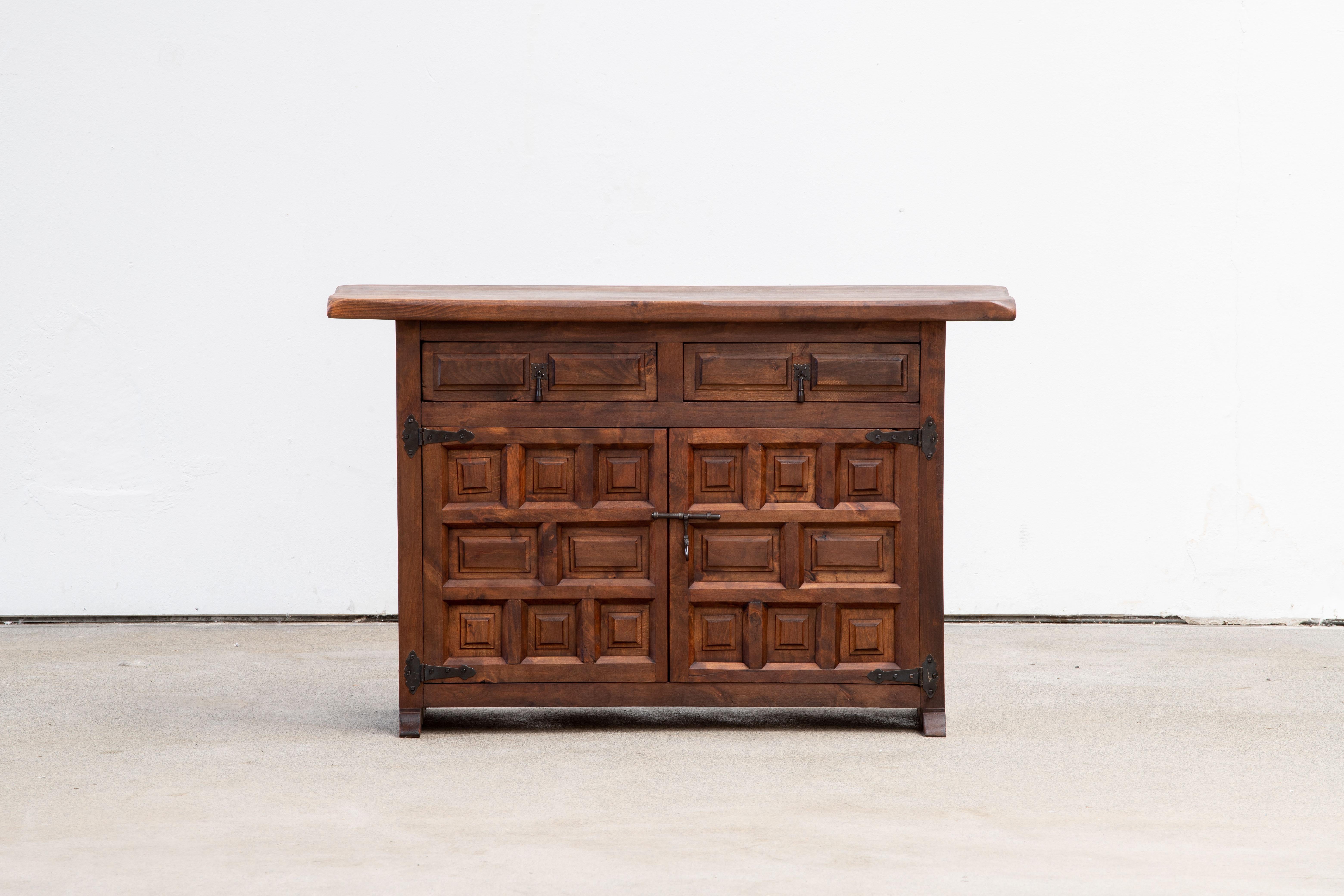 From Northern Spain, constructed of solid walnut, the rectangular top with molded edge a top a conforming case housing two drawers over two doors, the doors paneled with solid walnut, raised on a plinth base.
     