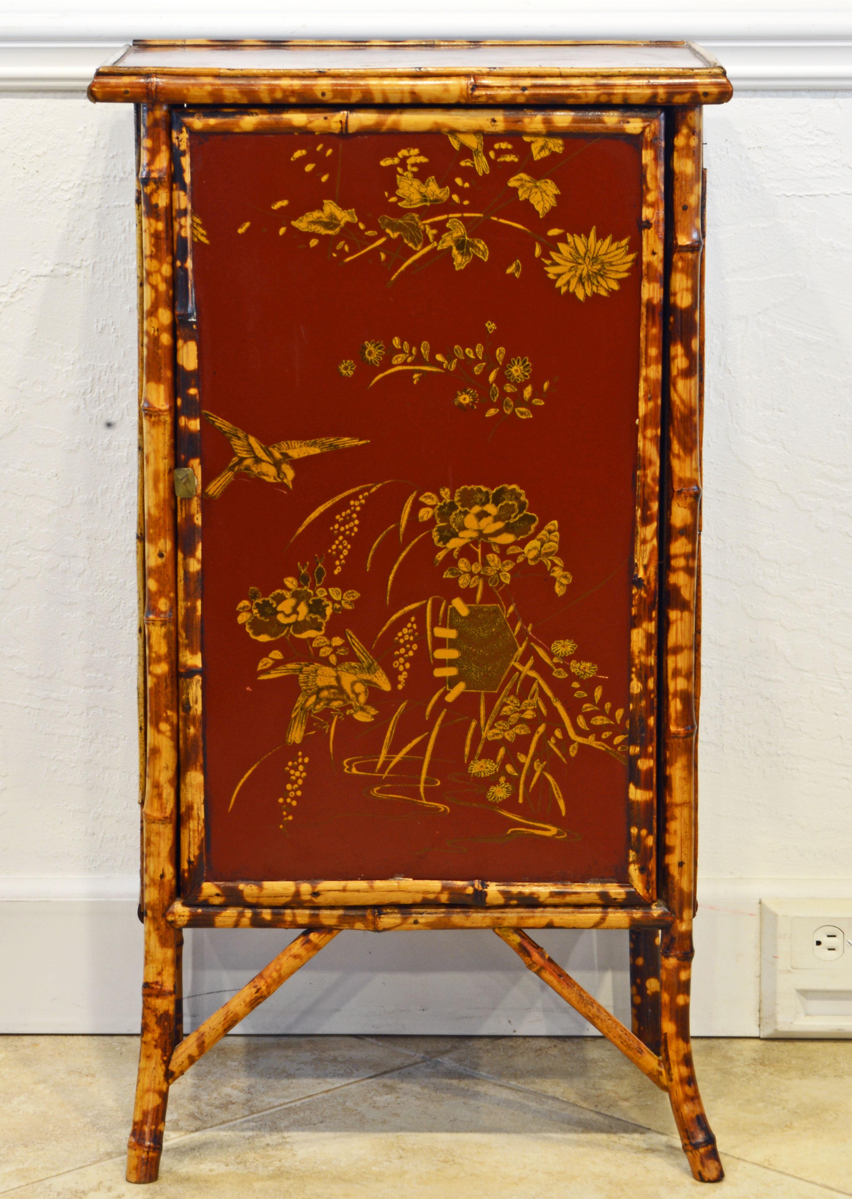 This late 19th century English bamboo and red lacquer cabinet features elaborate chinoiserie gilt decorations on the top, front and sides. The door opens up to a shelved interior and the cabinet rests on four slightly splayed bamboo legs.