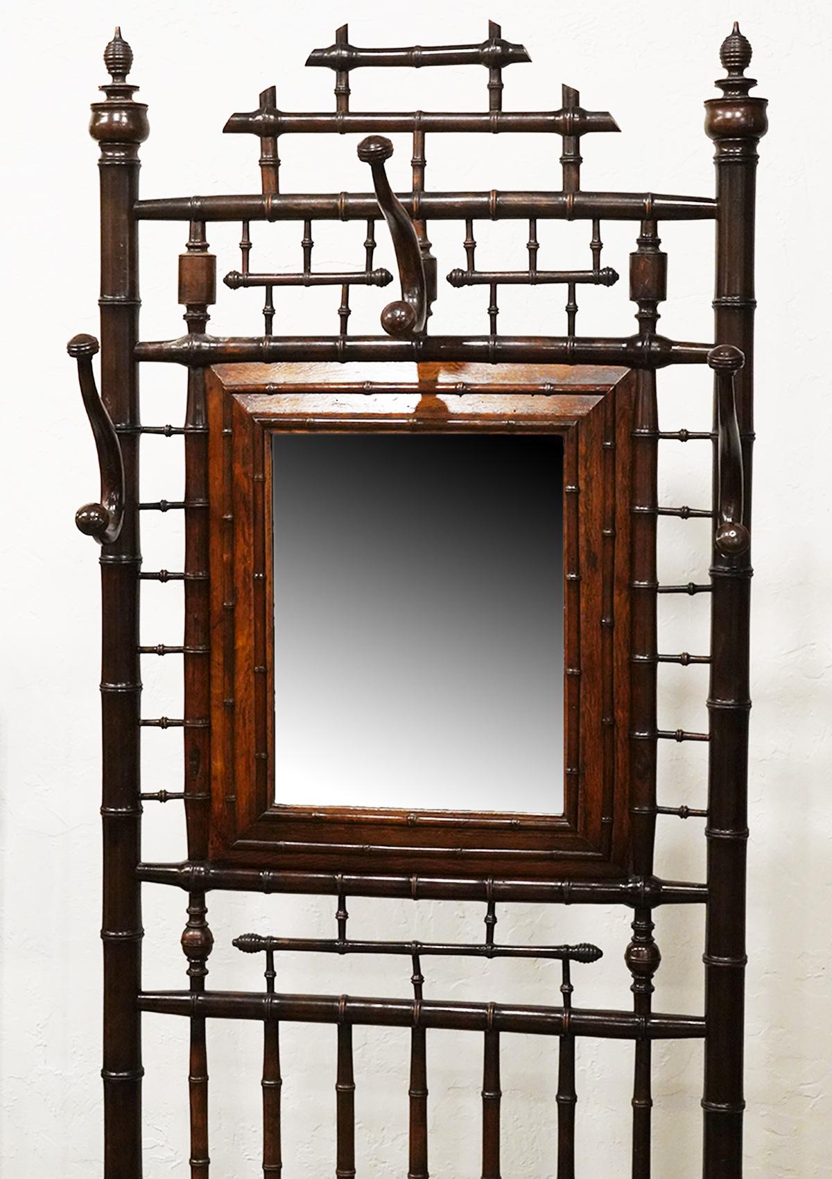 This unusually elaborated and detailed hall tree is made of turned elm simulating bamboo. The style was popular during the 1870s and 1880s Aesthetic Movement trend. The hall tree incorporates a beautifully framed mirror and an umbrella and cane rack