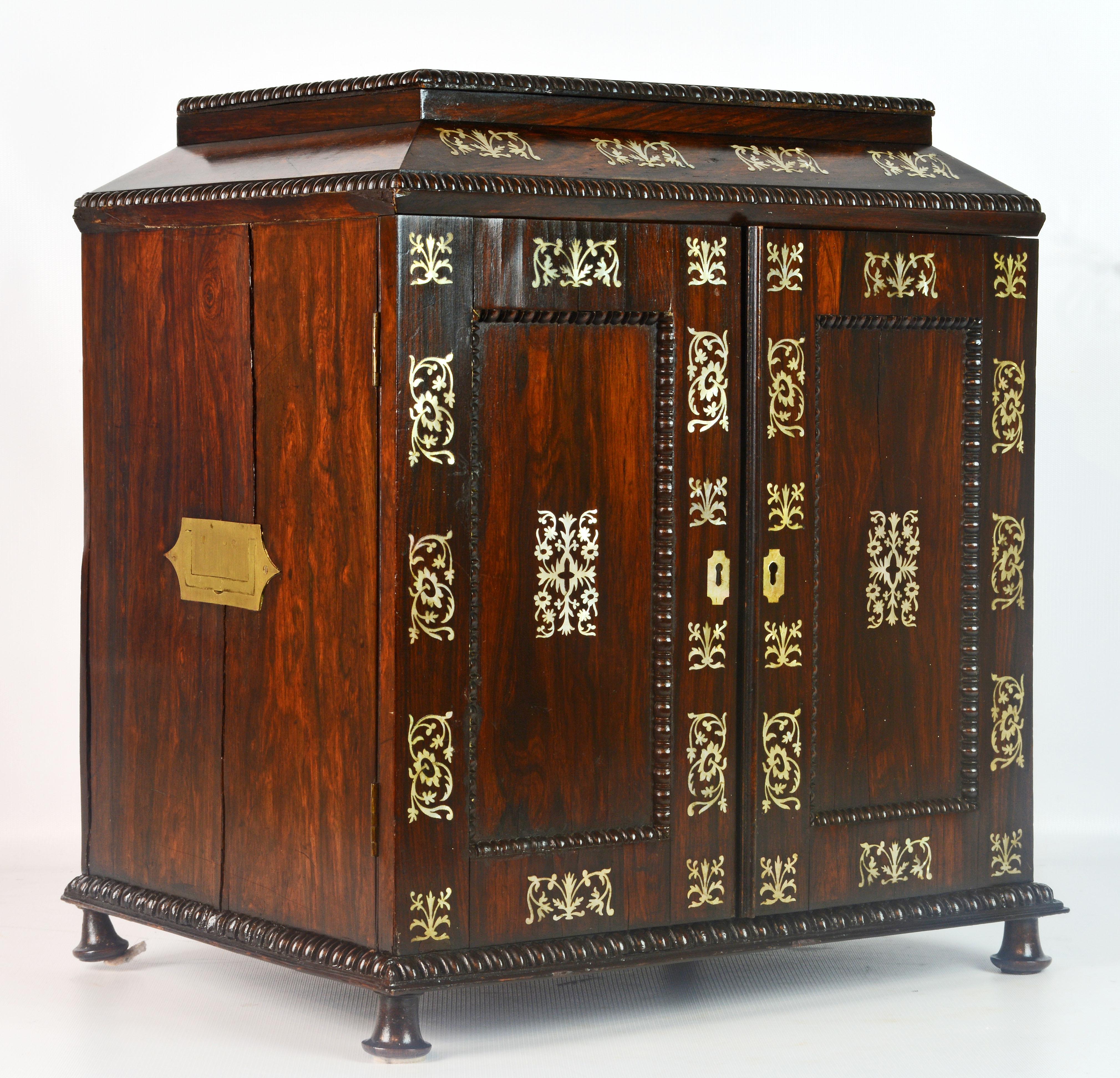 This is truly a treasure cabinet with its classic diminutive Georgian shape, beautiful warm colored rosewood and most importantly elaborately designed mother of pearl inlays. The doors open up to an interior with 6 long drawers and it offers flush