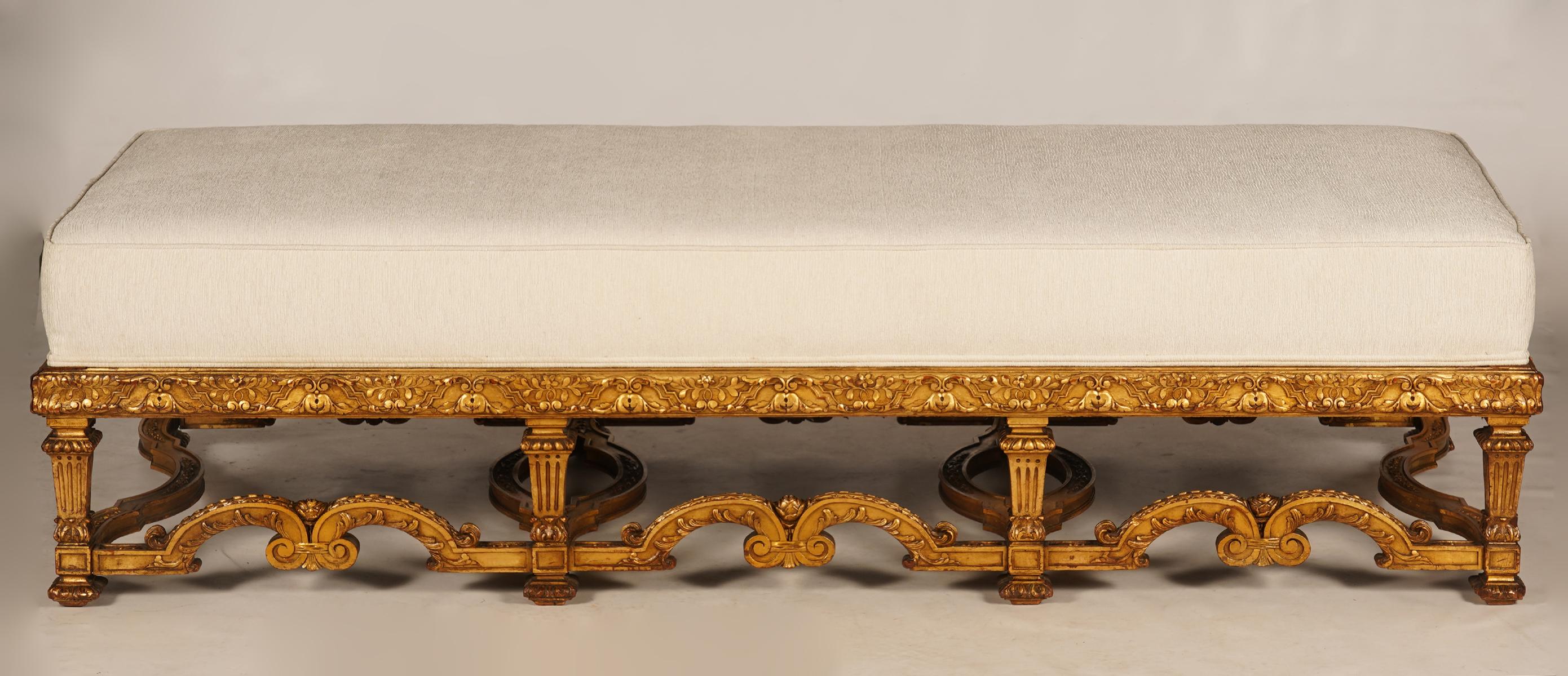 Of generous proportions this bench or daybed features 8 legs interconnected by carved stretchers in the Louis XIV style supporting a thick rectangular upholstered seat covered with off white fabric in mint condition.