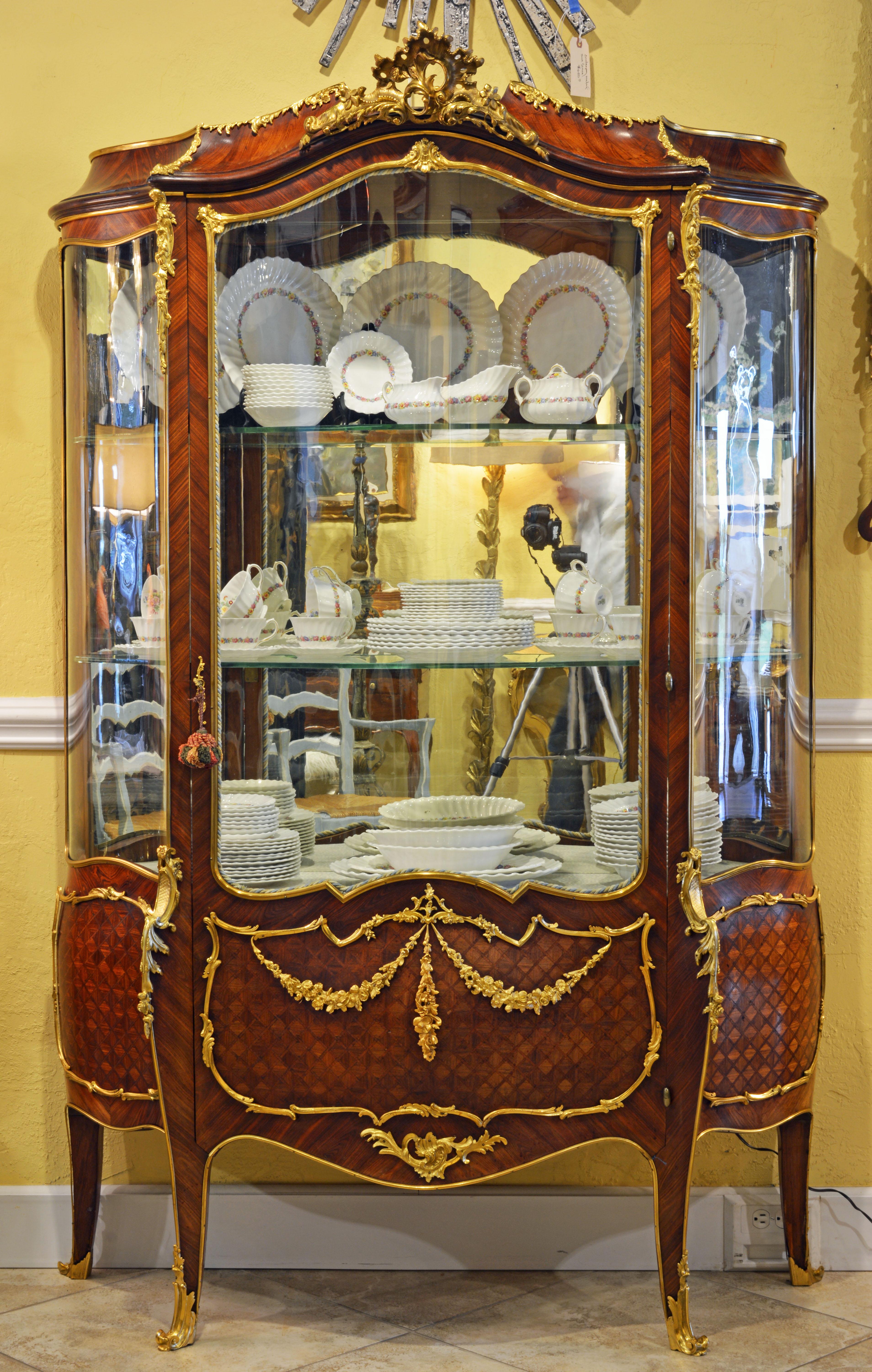 This magnificent French Louis XV style vernis martin vitrine or display cabinet features a kingwood and satinwood parquetry body adorned by richly detailed ormolu or gilt bronze mounts in the form of scrolls, leaf work and garlands creating an