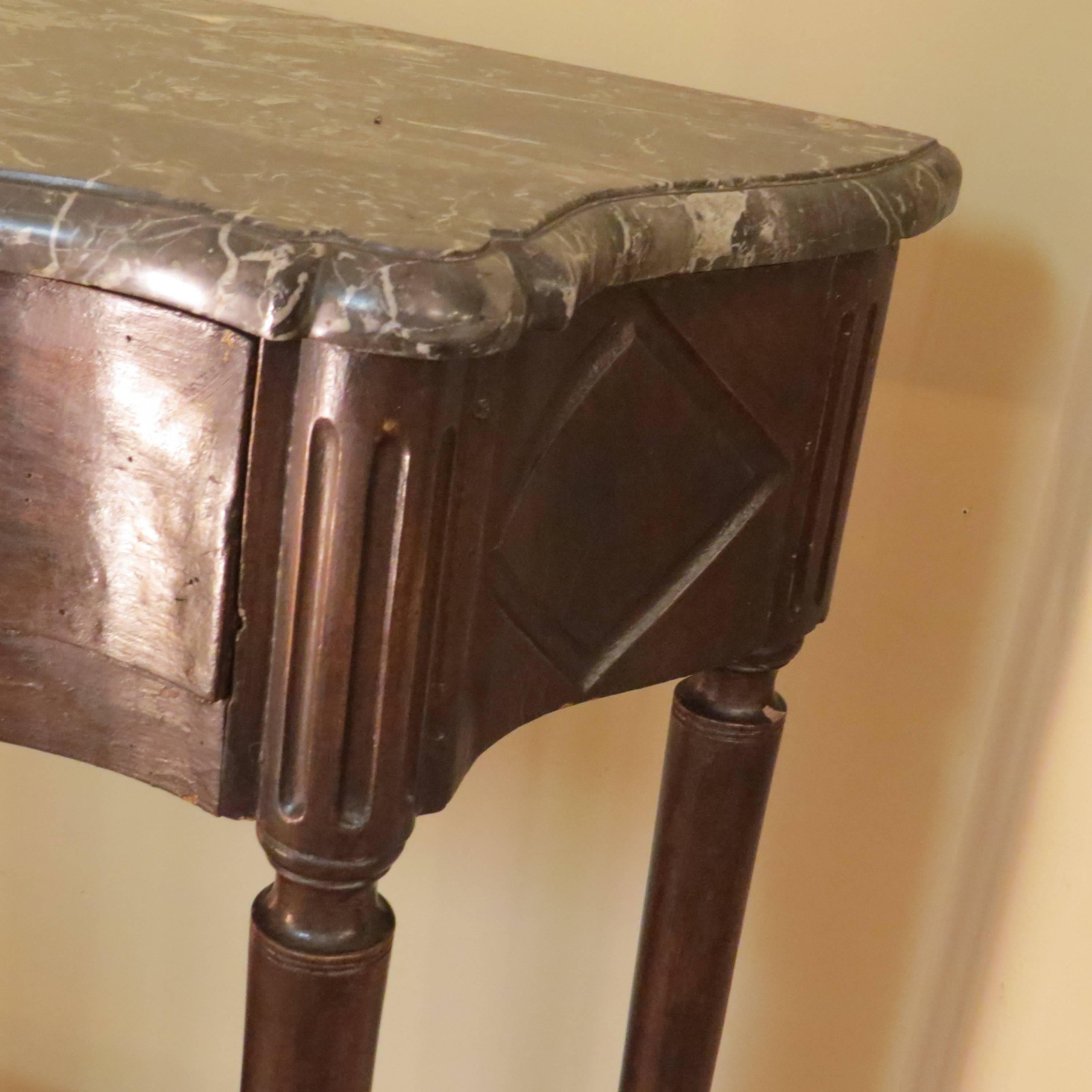 This petite console table has a shaped grey marble top. It has one drawer and a shelf below. It came from Paris and is made of stained wood.