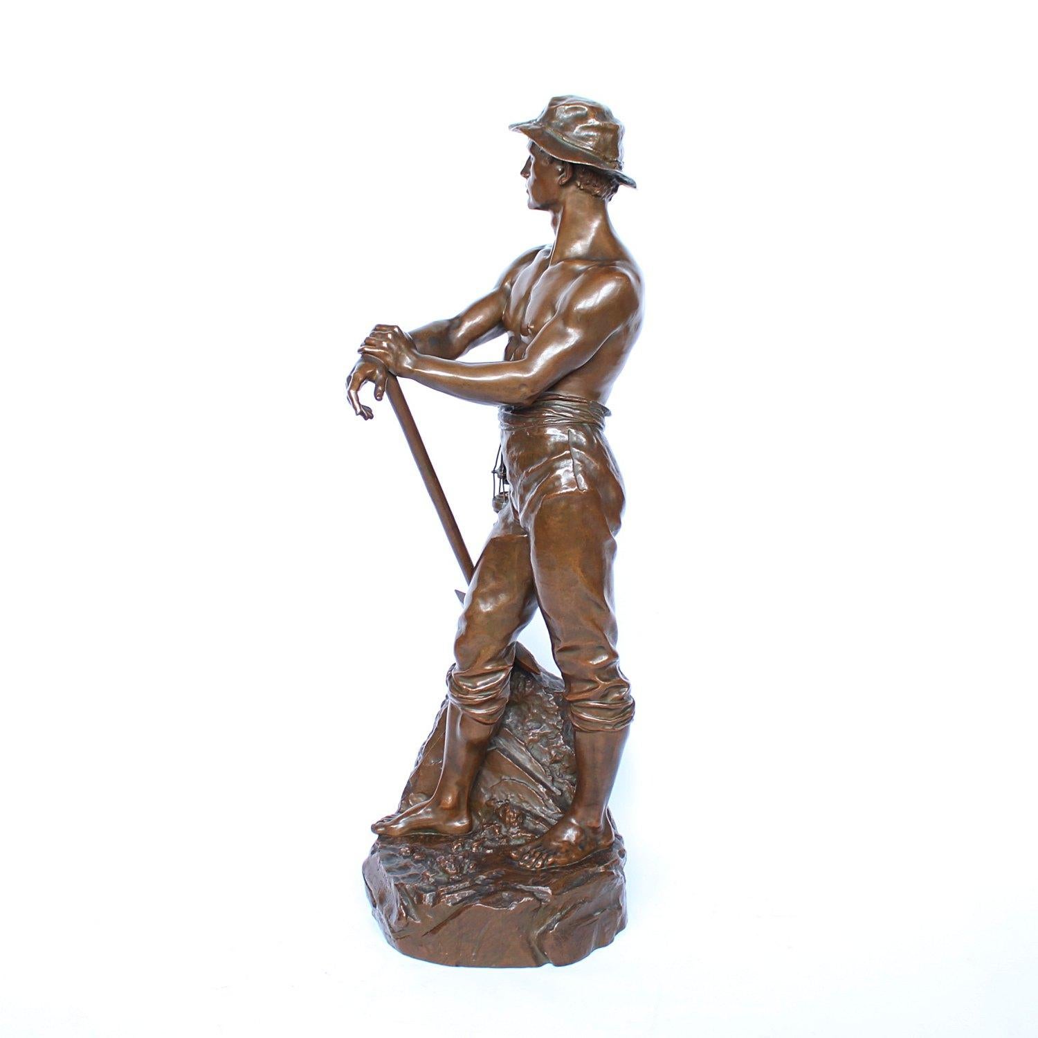 A large, 3ft tall bronze figure of a miner standing bare chested on an integral naturalistic base holding a pickaxe and a miner's lamp. Inscribed 'Mineur par Levy Salon des Beaux Arts', signed 'CH LEVY' and with the inscription: 'Bronze Garanti Au
