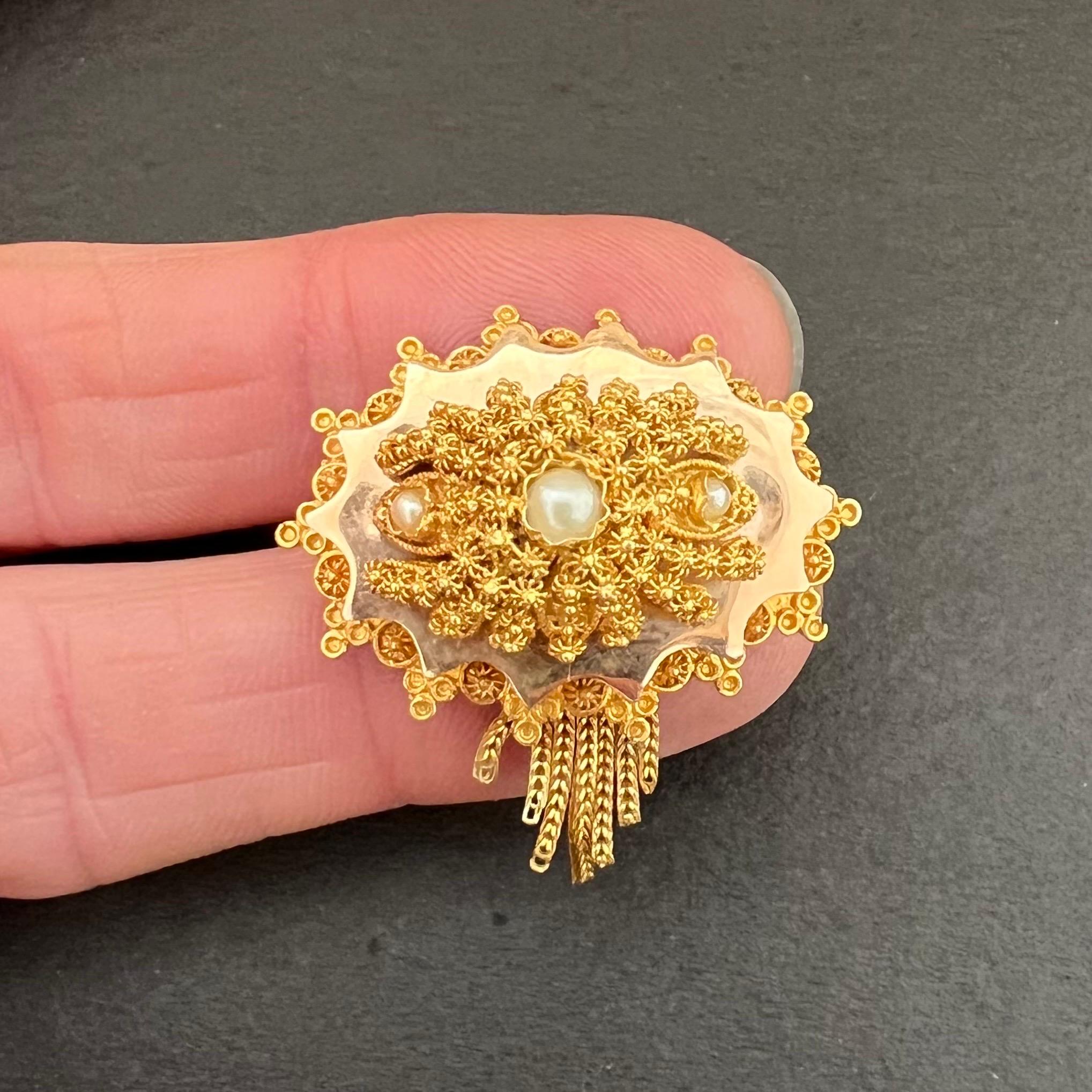 A 14 karat yellow gold cannetille brooch made in the Netherlands around 1900. The brooch is finely made with cannetille, gold twisted wire and buttons or knots decorate the top of the brooch. Between the ornate top of the brooch three seed pearls