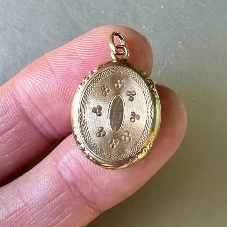 This mourning locket pendant was once worn close to someones heart. The locket pendant dates back to the 19th century and is made of 14 karat gold. The front of this oval-shaped pendant is beautifully engraved with ornaments while the side is