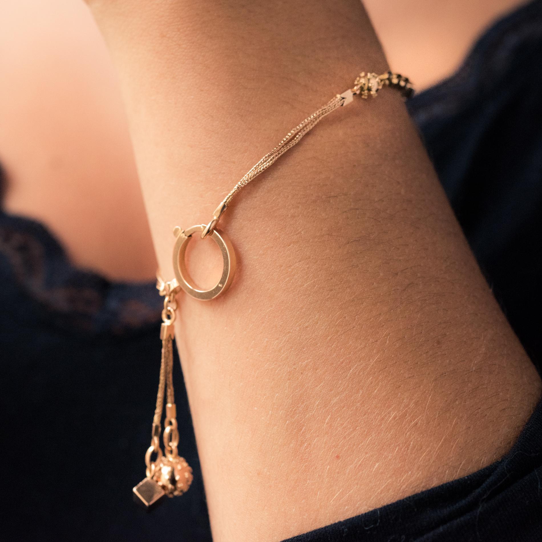 Bracelet in 18 karat rose gold, weevil hallmark.
Former small vest chain, it is formed of a column link which retains a convict link pattern alternating with small gold cubes and studded pearls. The clasp is a large antique spring ring. A tassel is
