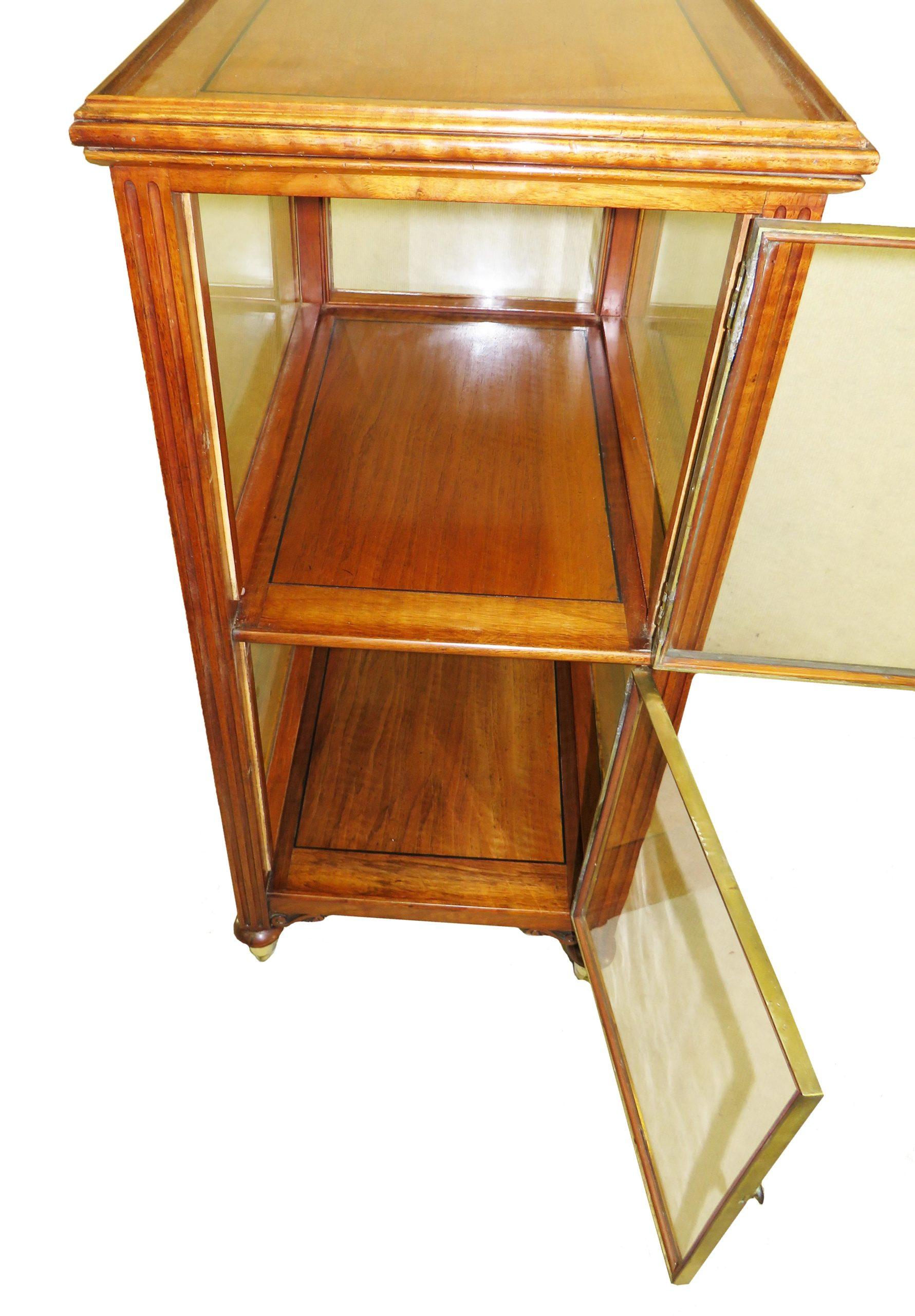 19th Century (1850s) French walnut central standing display cabinet (central standing bijouterie) with two end doors and brass molded decoration raised on elegant turned feet with original brass castors. 
 