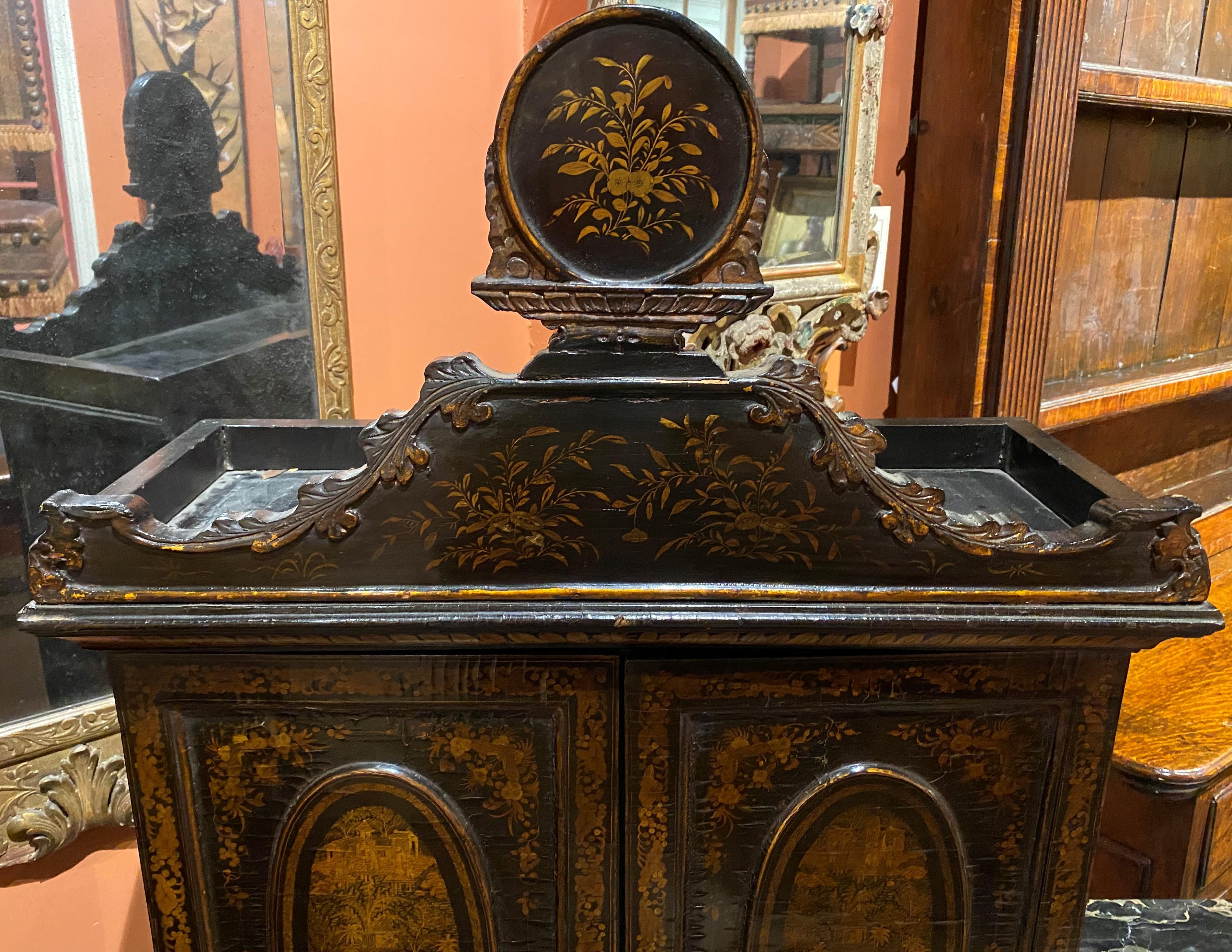 A fine three-piece diminutive black lacquer secretary desk with extensive chinoiserie or japanned decoration, including a base table, brass-handled lap desk, and two door cabinet with compartmentalized interior. The cabinet has a carved crest with