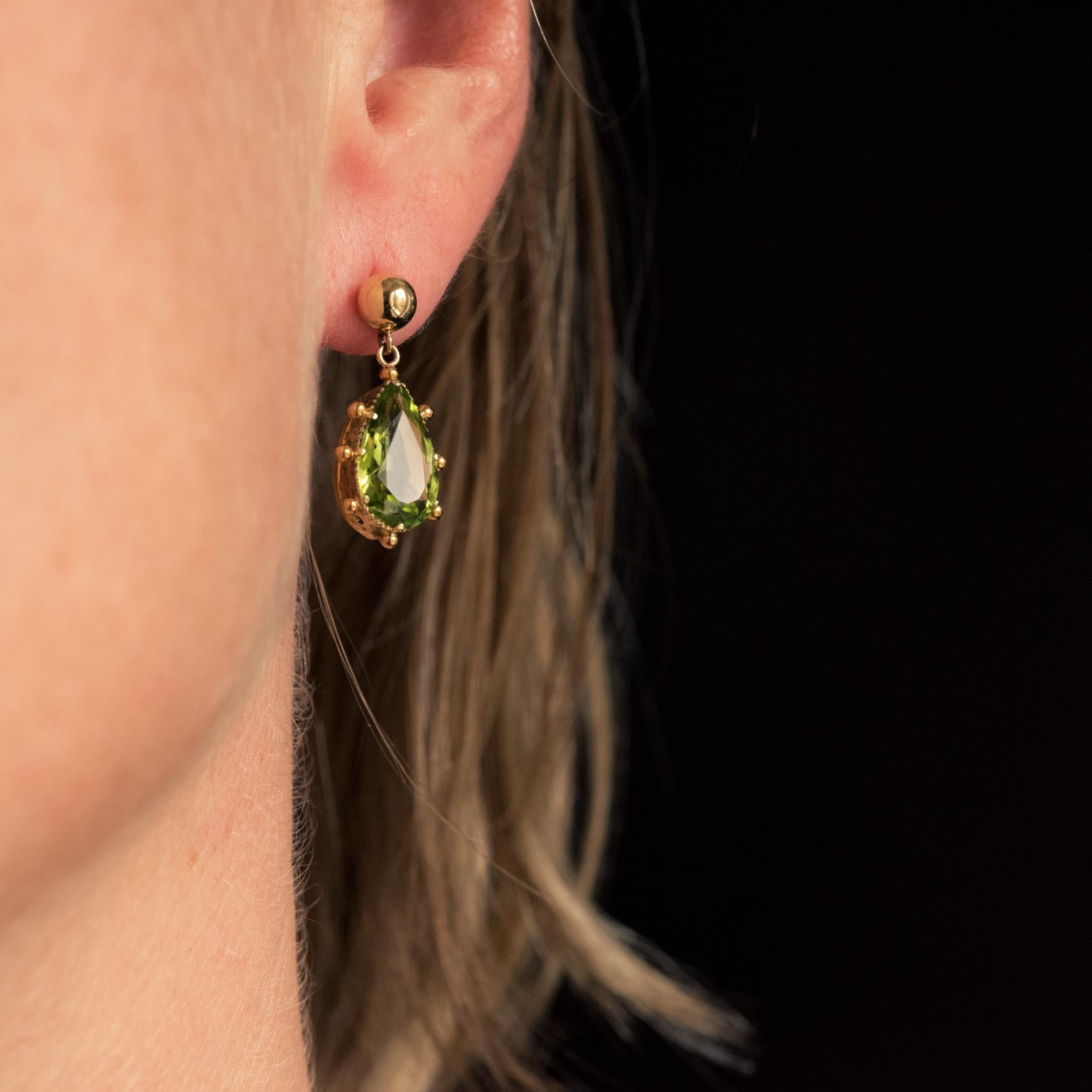For pierced ears.
Earrings in 18 karat yellow gold.
Sober and elegant, each antique earring is made of a gold pearl which holds a pear-shaped peridot in a tassel, edged with a pearl. The attachment system is butterfly.
Total weight of peridots :