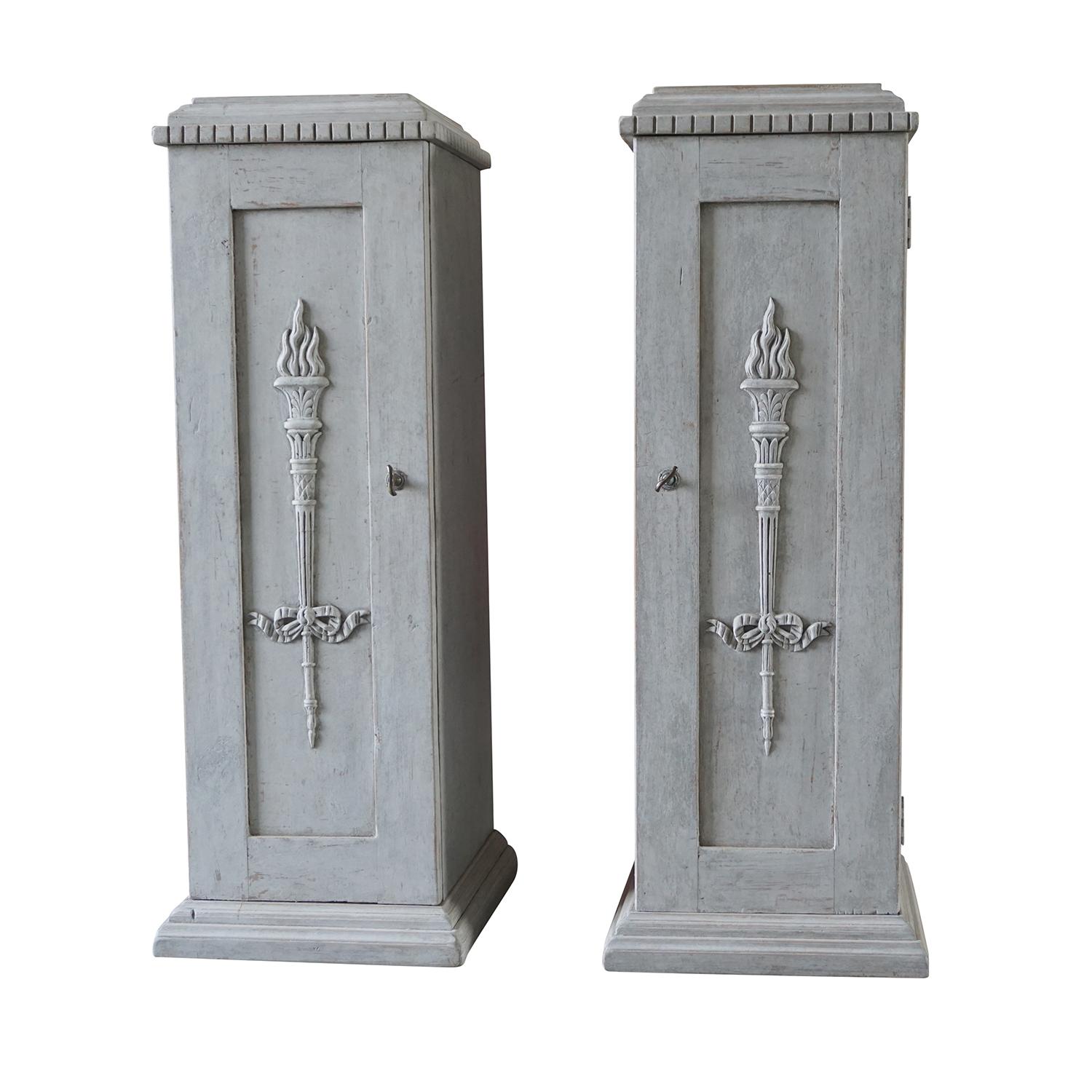 An unusual pair of Swedish side cabinets made of grey painted pinewood with one door and keys, featured inside with two white front drawers. The hand carved pedestals are in good condition and detailed in the neoclassical Greek style with their