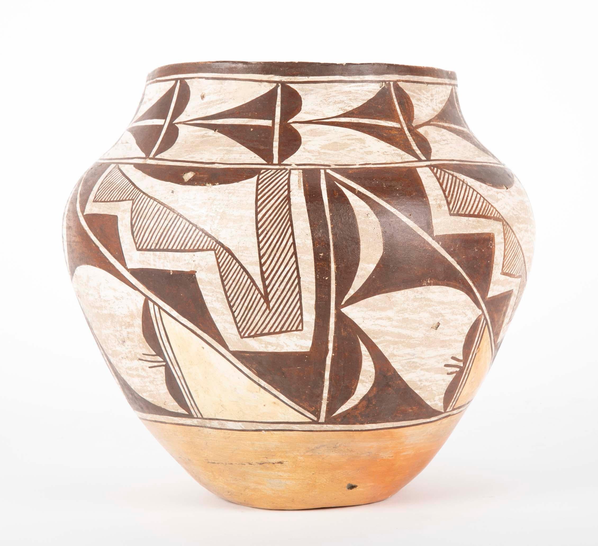An Acoma clay vase from the 2nd quarter of the 20th century with black geometric line decoration on white background. Traditional Acoma pottery is made using a slate-like clay found within the hills surrounding the Pueblo. The pots are made using a