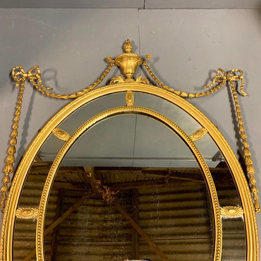 English 19th Century Adams Style Oval Gilt Mirror with Tied Ribbons and Urn Decor