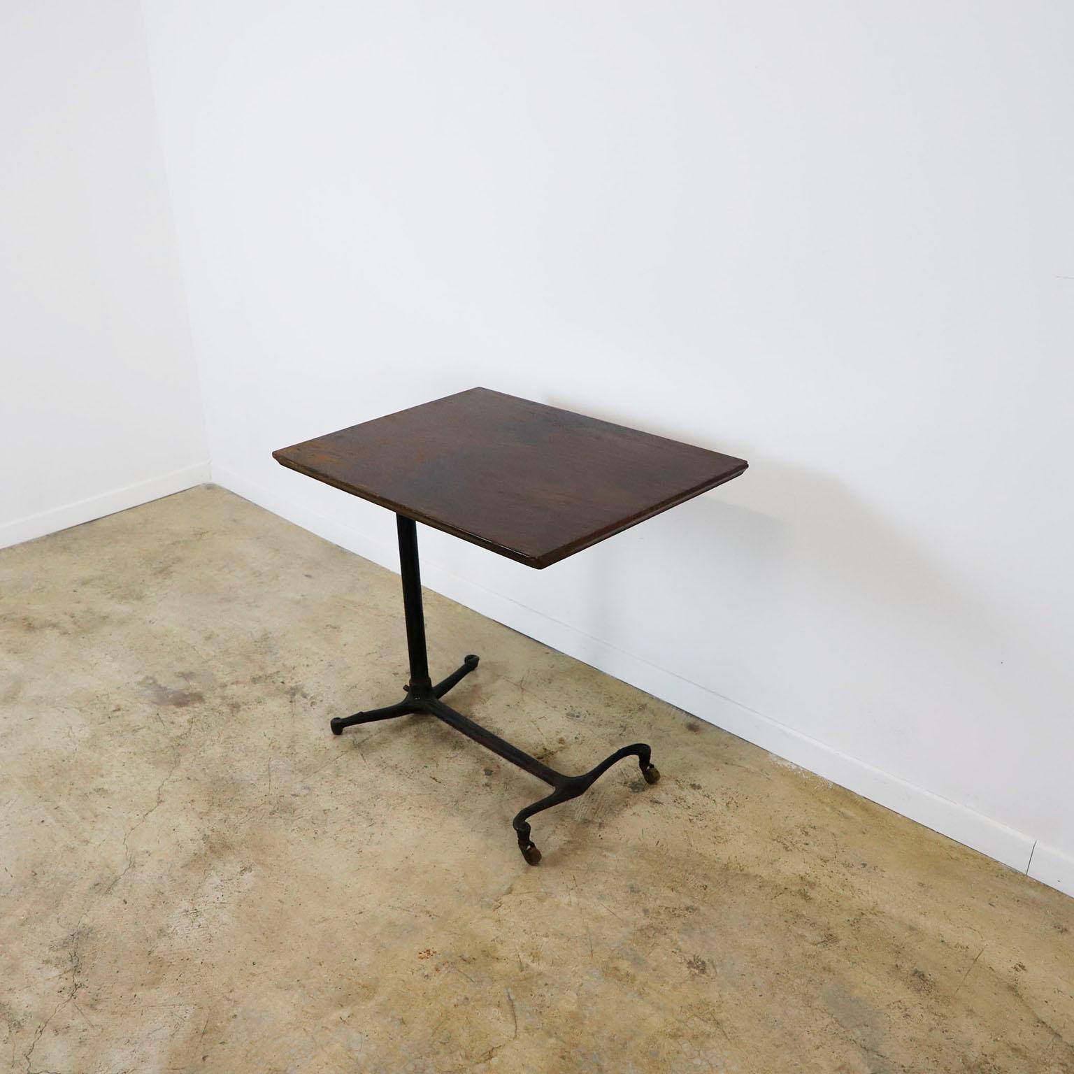 Te ofrecemos esta mesa de dibujo regulable del siglo XIX en hierro fundido. El tablero de la mesa es original y está hecho en roble macizo, apoyado en una base de hierro finamente fundido con un par de ruedas hechas en madera. La altura se ajusta de