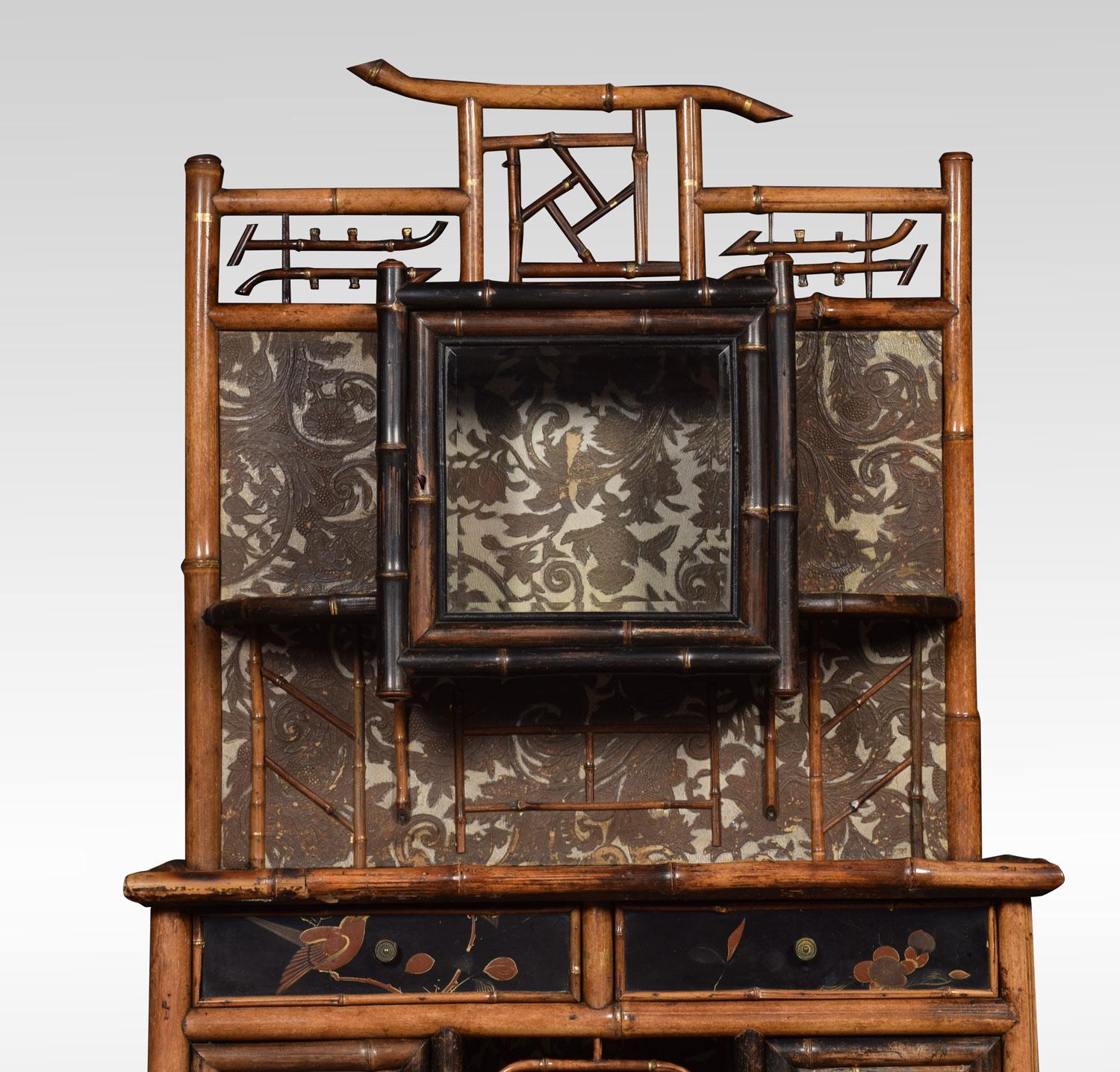 Aesthetic movement bamboo and lacquer cabinet having an openwork pediment above a beveled glass door flanked by a small shelf to each side, the lower section with rectangular top over a pair of frieze drawers and two small paneled doors centering an