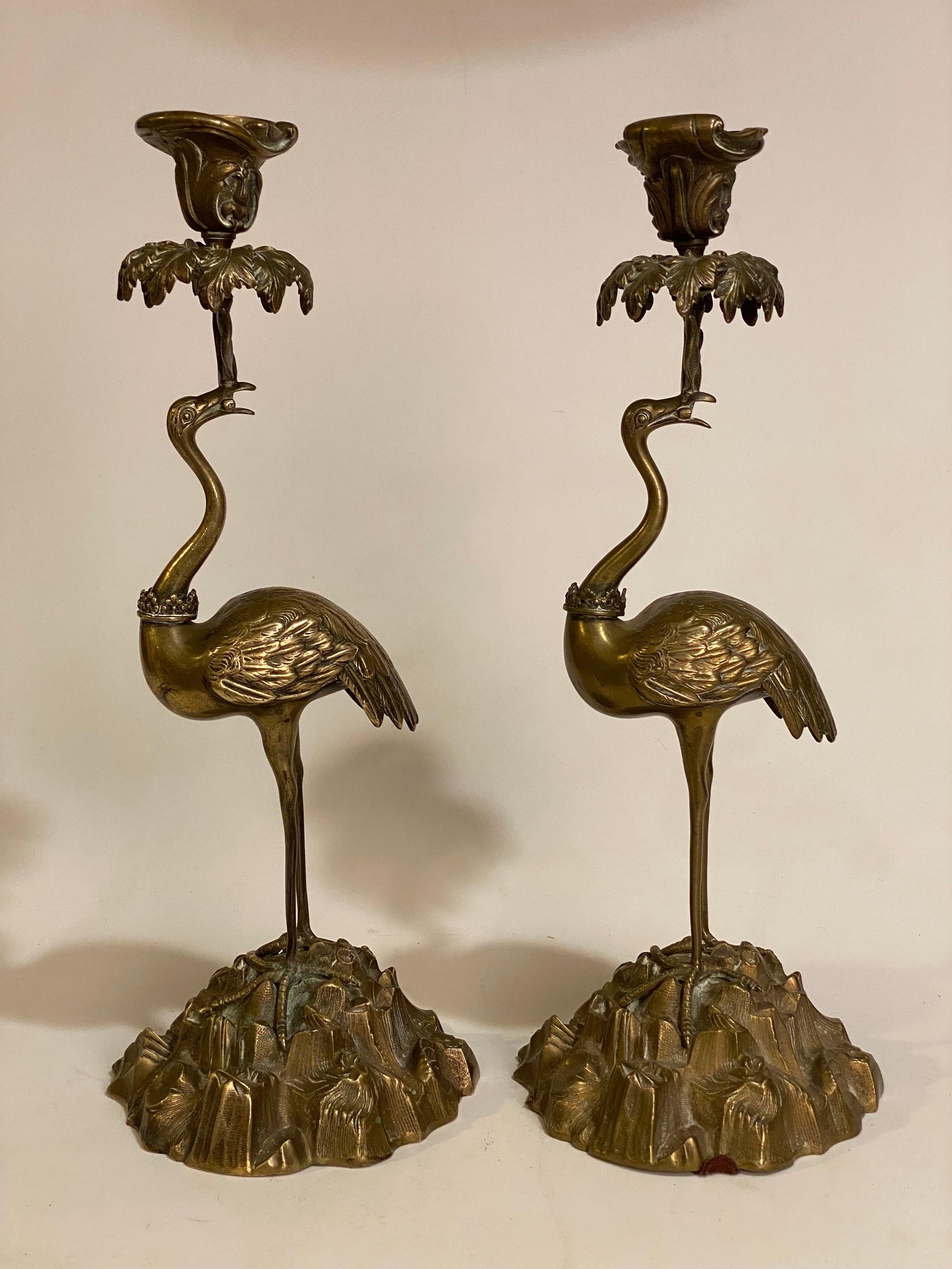 A sumptuously cast pair of bronze flamingo candleholders. From the bases to the tropical palm tree tops, the pair has no equal for precision or decorative appeal. The flamingos set upon a rocky base of sea shells, sea plants  topped with palm trees