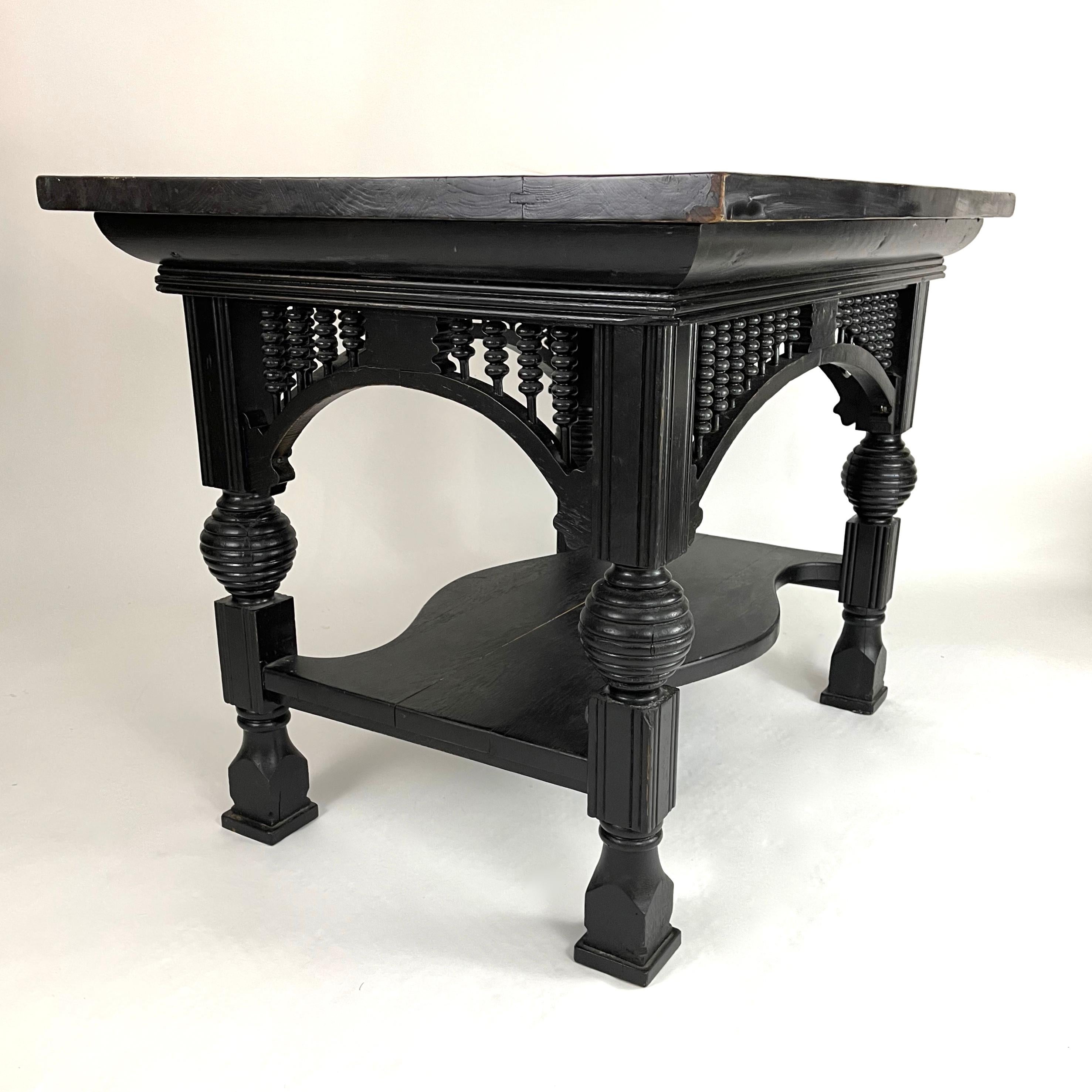 A wonderfully graphic and sculptural 19th century Aesthetic Movement period table, in oak with later black painted surface, the rectangular top over turned spindles joined by arched brackets attached to square section and circular beehive turned