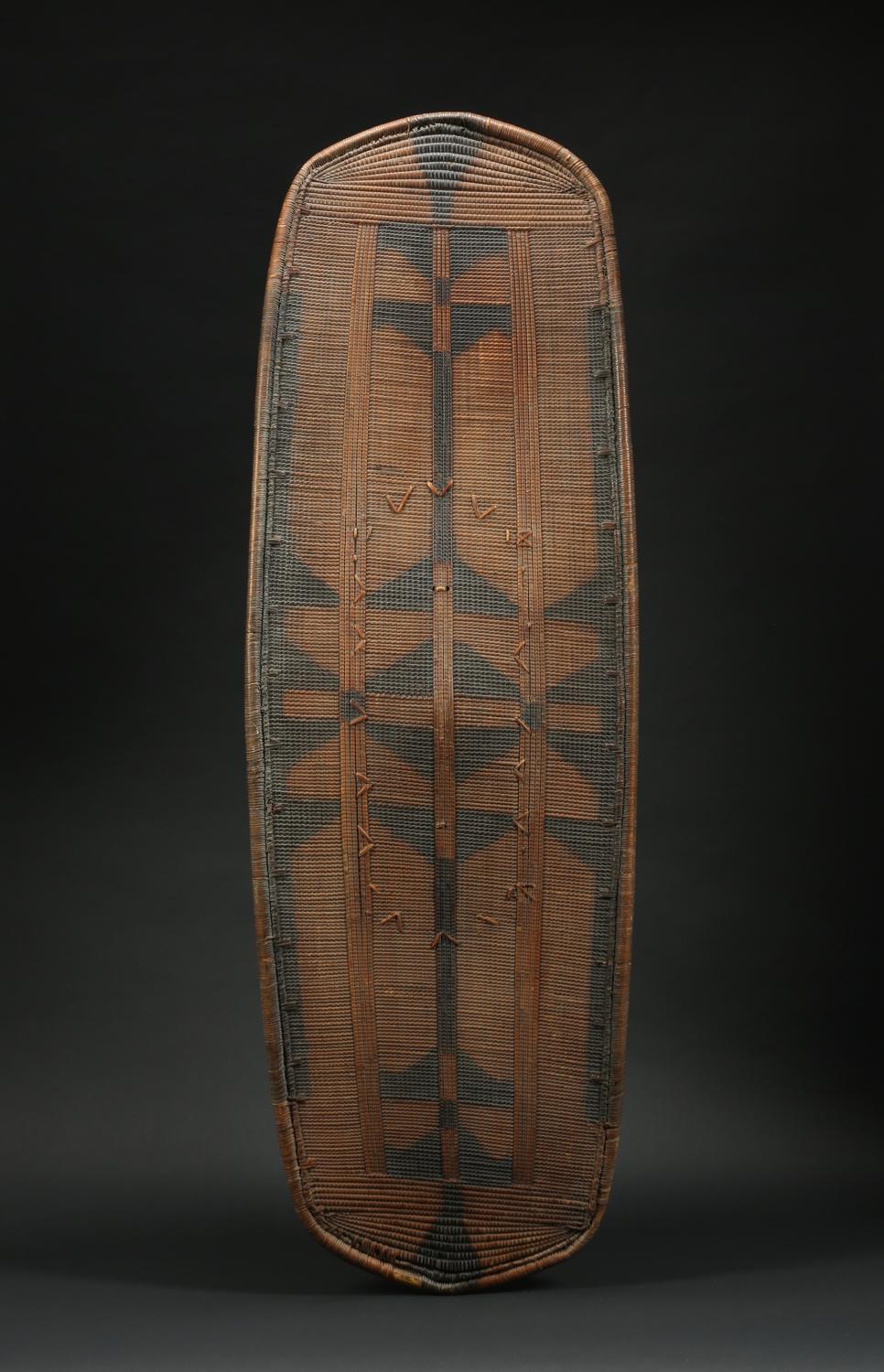 A finely woven Banda war shield from Zaire. The black and yellow rattan and wicker is tightly woven to make a visually striking pattern, and is in fine condition. The original handle is carved out of wood and lashed onto the shield with rattan