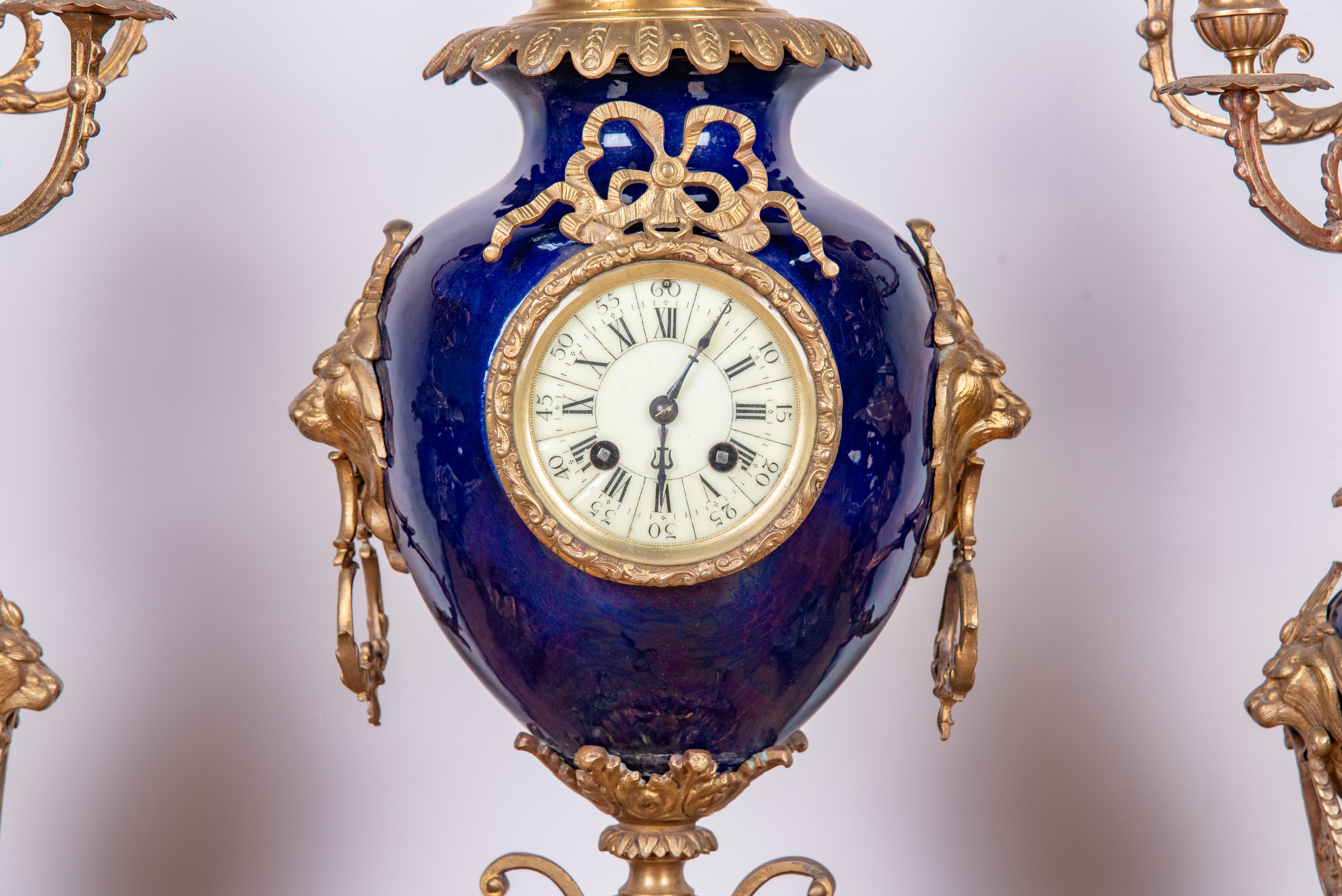 Ce magnifique ensemble de pendules de cheminée de style Louis XV du XIXe siècle, fabriqué dans le style de Sèvres, incarne l'opulence et l'élégance des arts décoratifs français. L'ensemble comprend une horloge de cheminée au design complexe