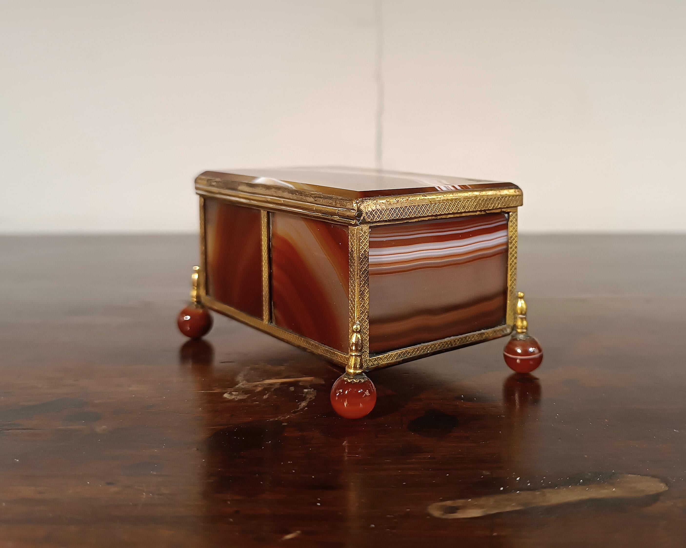 Belle boîte à bijoux en agate avec finitions en laiton doré, de petite taille. Les pieds tournés sont également en agate, ce qui confère à la pièce une élégance particulière. La pierre dure, de par sa particularité et son travail, confère au