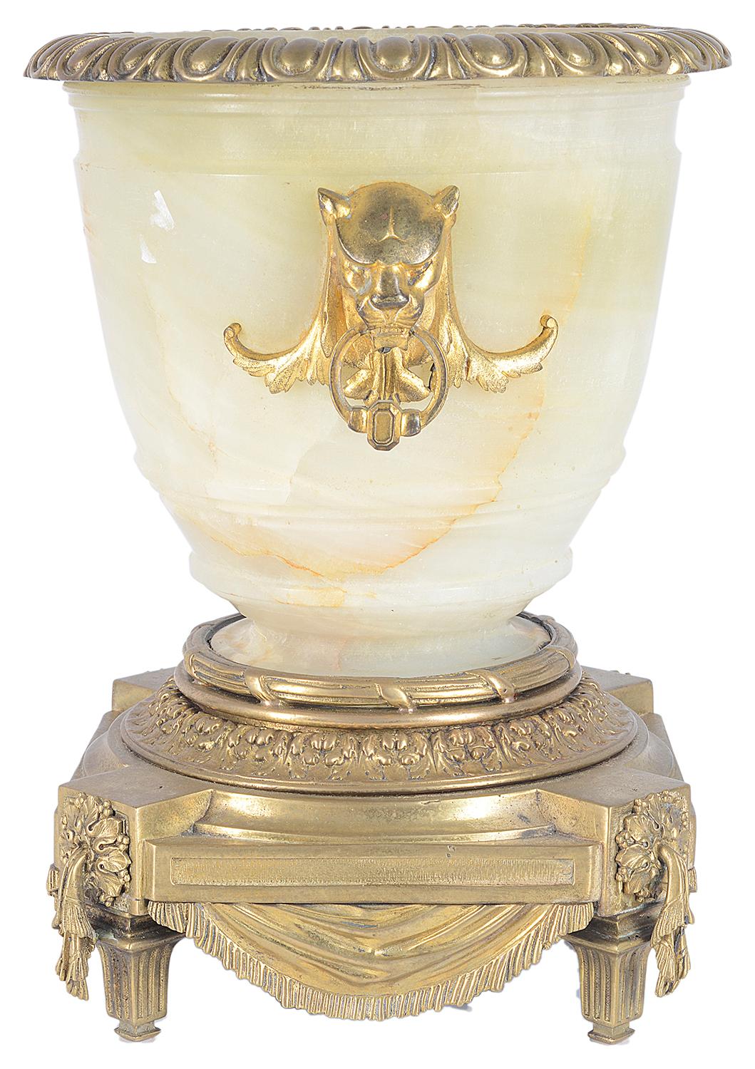 A good quality 19th century classical Alabaster and gilded ormolu urn. Having an egg and dart moulded ormolu rim, Leopard mask ring drop handles on either side, translucent Alabaster to the urn and raised a classical platform base with swag