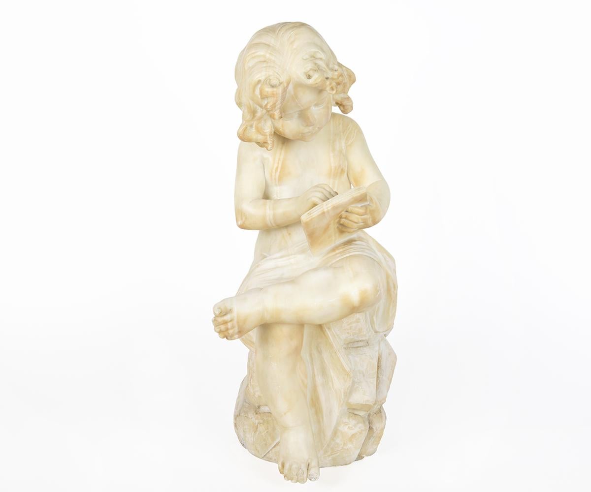 A beautiful antique Italian alabaster sculpture of a young girl sitting on rock reading a book.