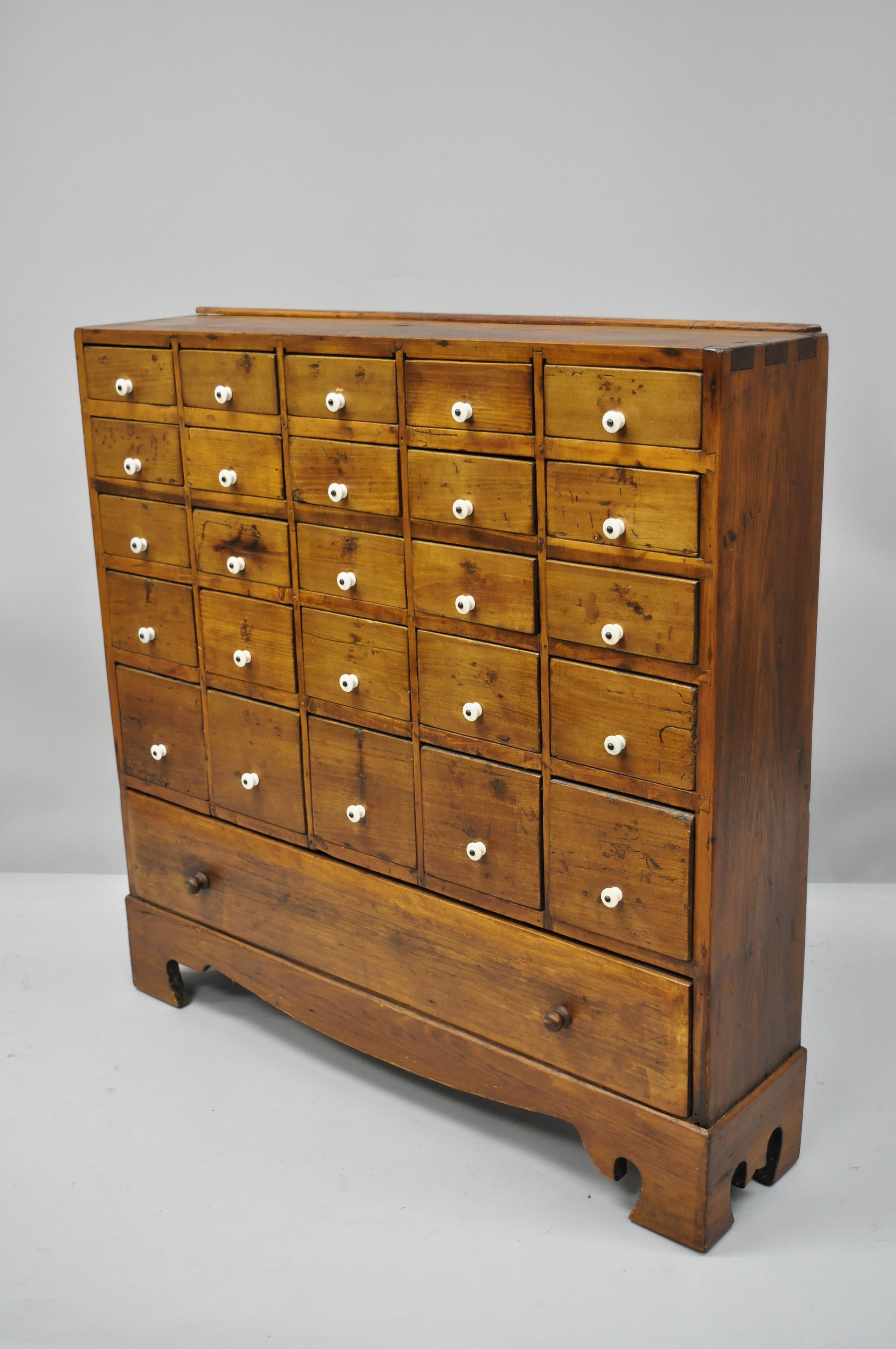 19th century American 26 drawer dovetailed pine wood apothecary cabinet chest. Item includes dovetailed joinery, remarkable antique patina, solid wood construction, 26 dovetail drawers, very nice antique, quality American item, circa early 19th