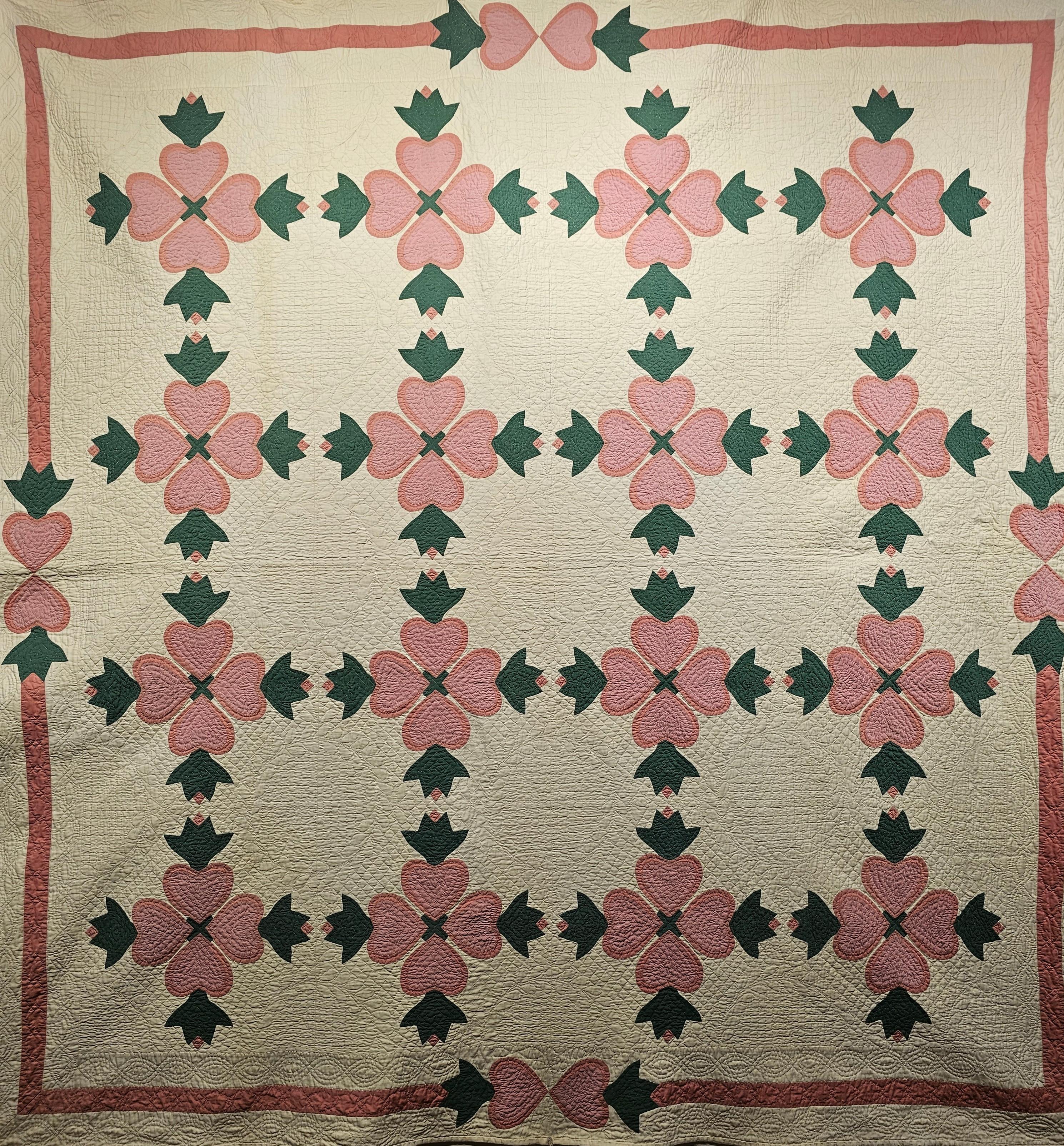 This beautiful American Applique Quilt was hand stitched in the late 1800s in Pennsylvania in the United States. The American Applique Quilt is in a “Hearts and Tulips” pattern with pink hearts with green tulips on an ivory background.  The quilt
