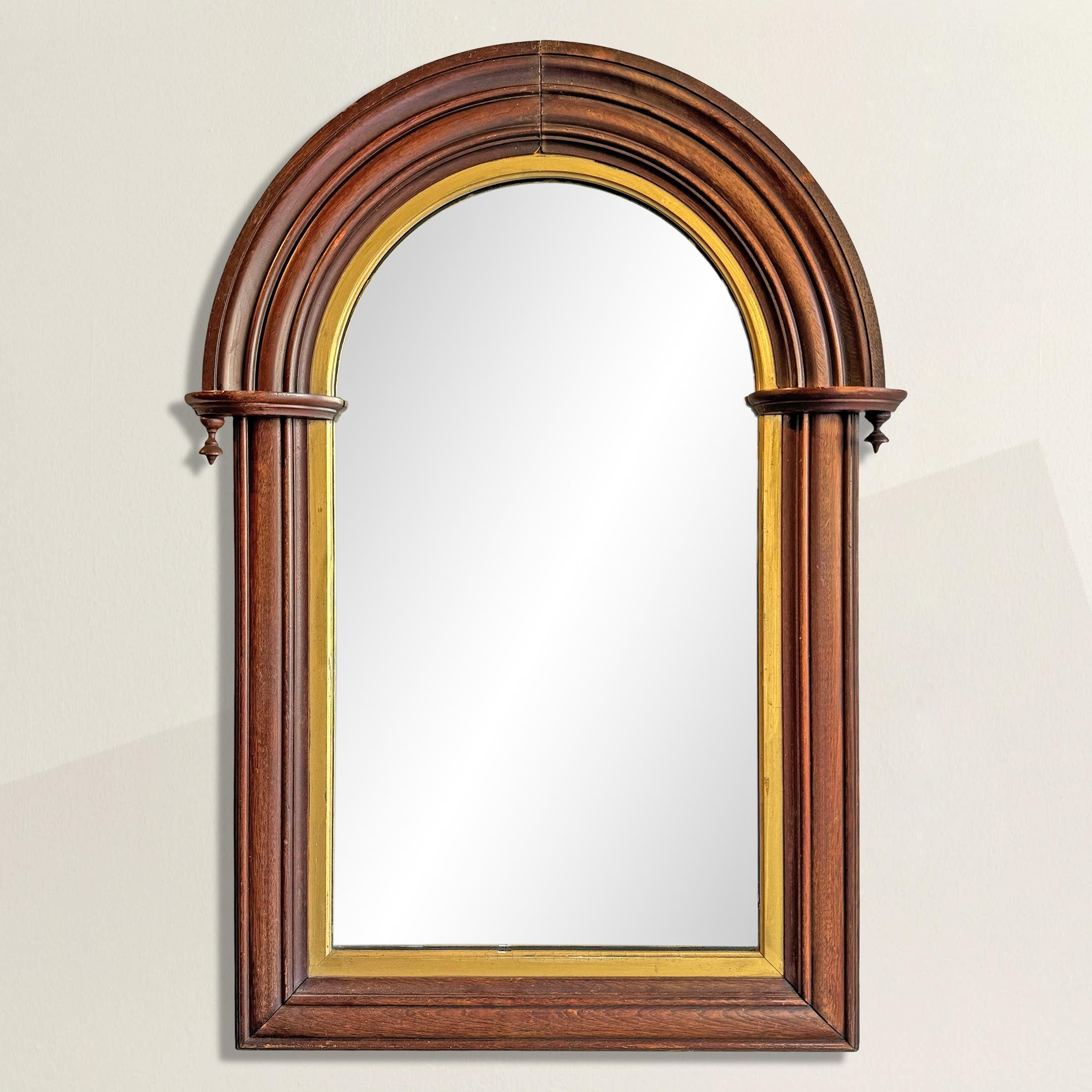 A mirror that doesn’t just reflect but refines: this 19th-century American example is carved of deep, lustrous mahogany, its arched top giving it a quietly architectural presence. Along the inner edge, a gilt fillet gleams—subtle, not showy—catching