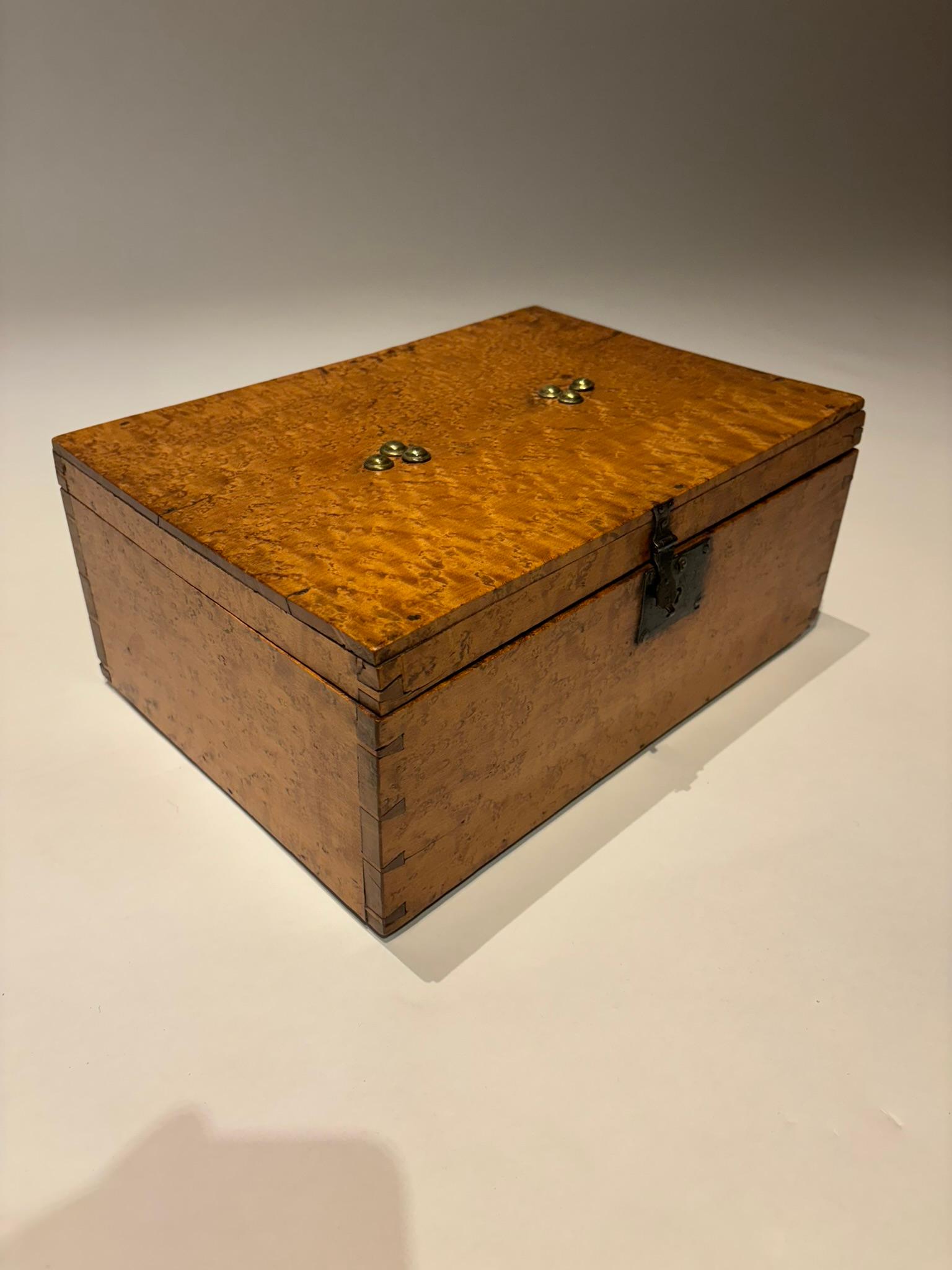 19th century birdseye maple box with brass nail head decoration and iron lock plate and hasp. This box is hand crafted with beautiful dovetail joints visible on the corners, evidence of true craftsmanship. A wonderful glowing patina that only comes
