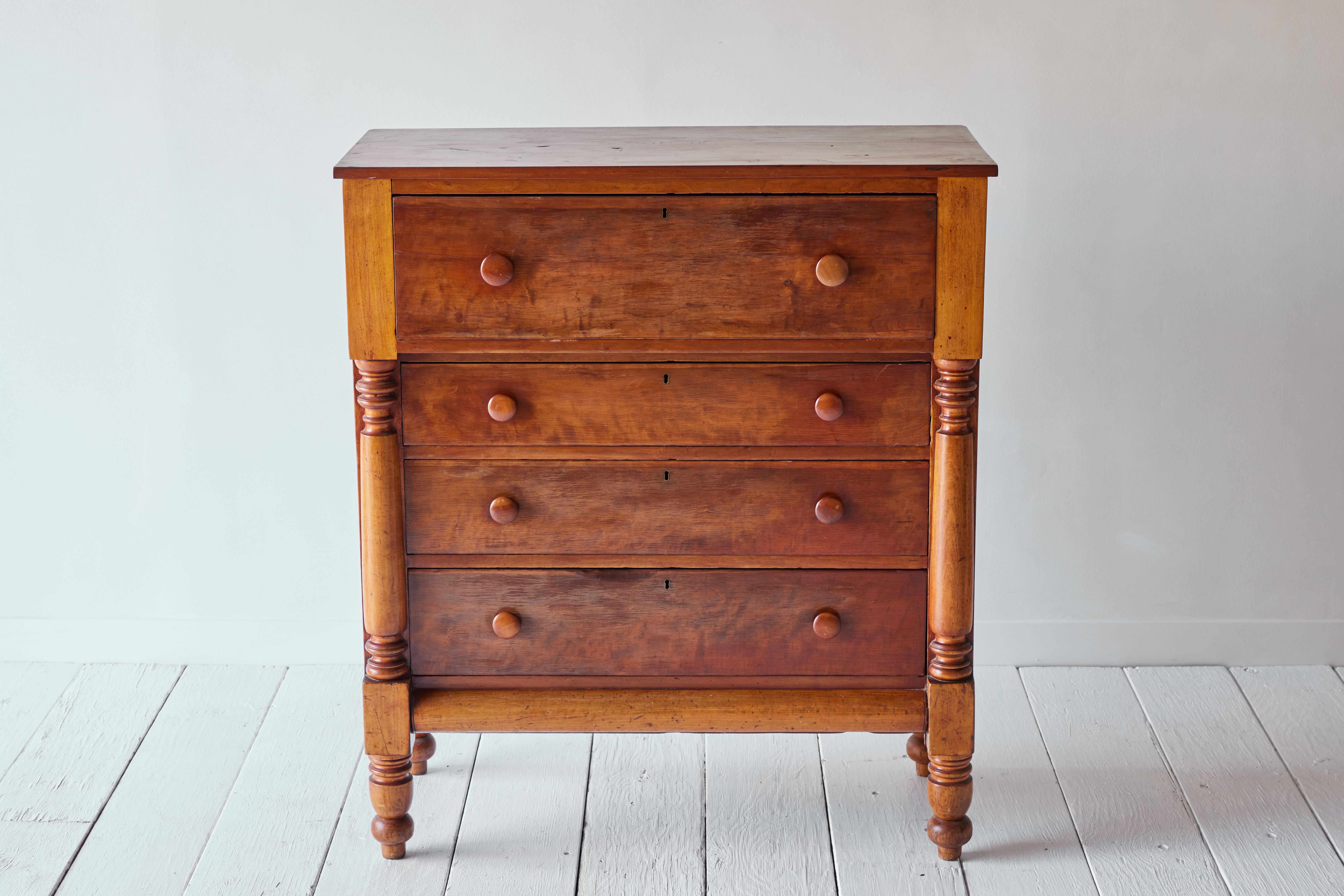 Antique American chest of drawers circa 1840 with turned wood mushroom knobs and an overhanging top. The first drawer is large with three graduated drawers below, turned front legs and straight back legs. The chest has a beautiful patina and each