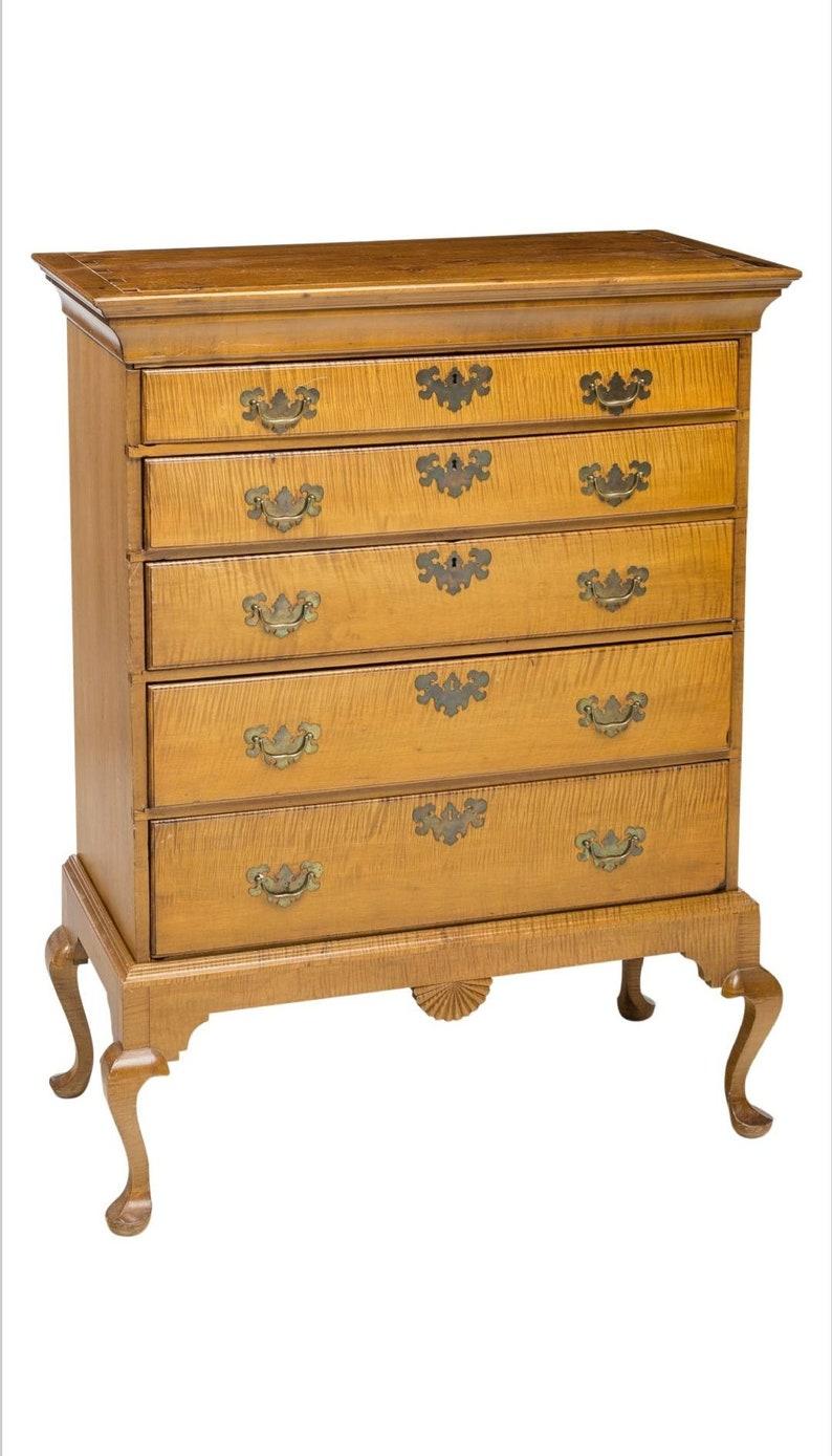 An antique American Chippendale style curly maple (also called tiger or figured maple) chest on stand from the 19th century. This curly maple highboy has five dovetailed graduated drawers with original pierced batwing brass handles and escutcheon,