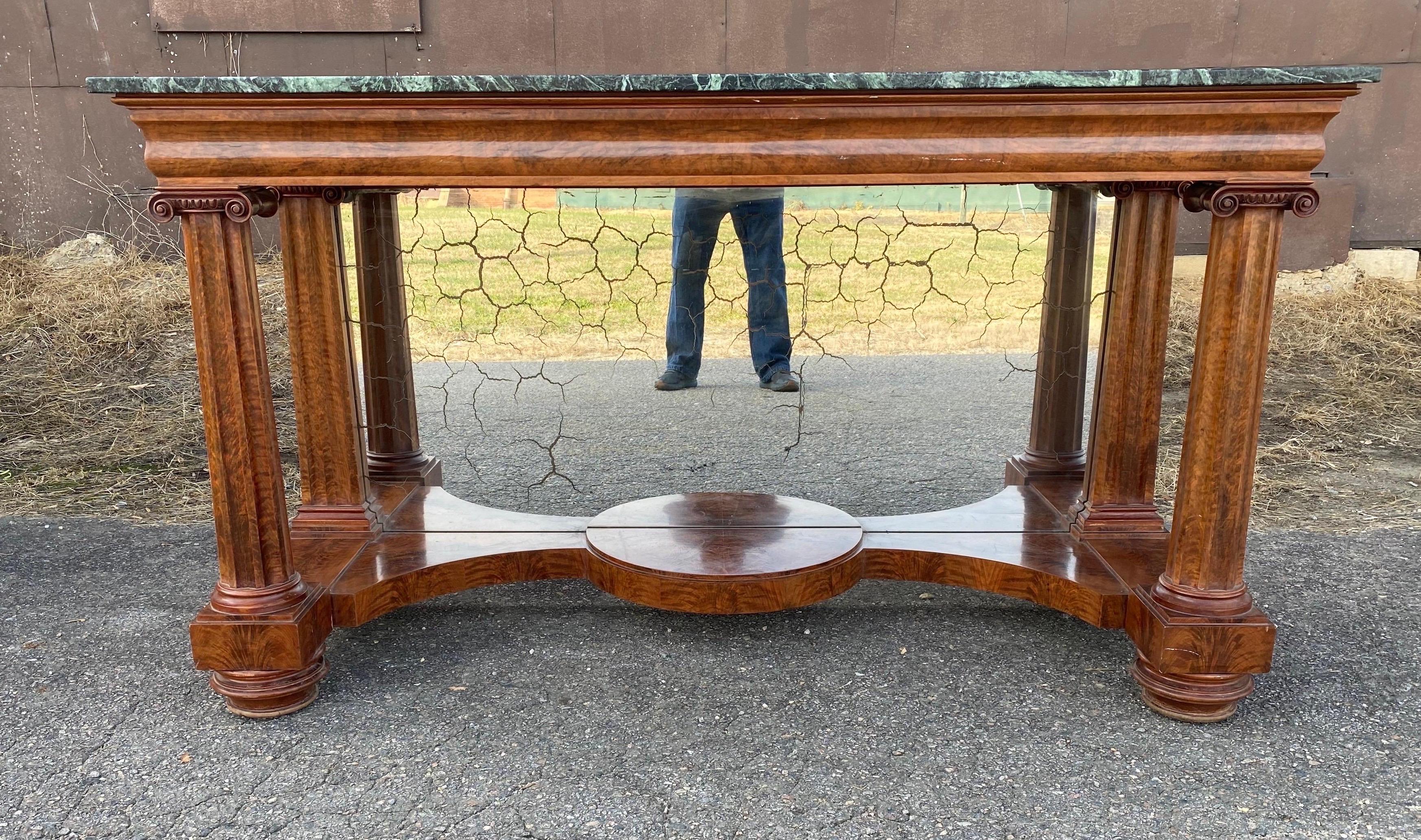 Impressive 19th century American Classical period mahogany marble top console with mirrored back. The console has highly figured mahogany veneered columns and capitals encasing a mirrored back and curved base. There are two drawers that slide out