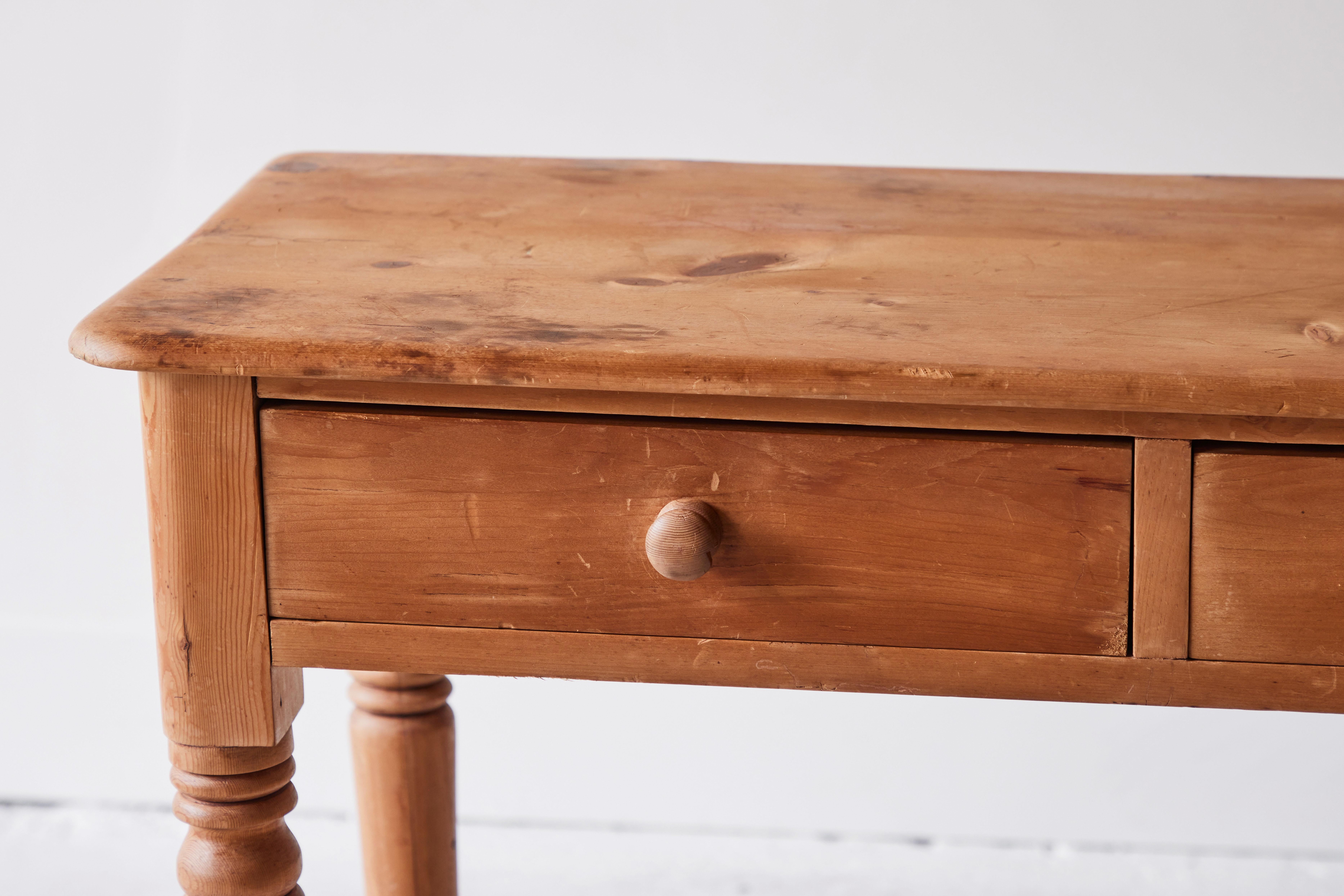 Rustic 19th century American country table featuring a beautifully aged pine patina, two drawers and beautifully turned legs. This style of furniture was generally made by non-professional or local craftspeople and was designed to emulate