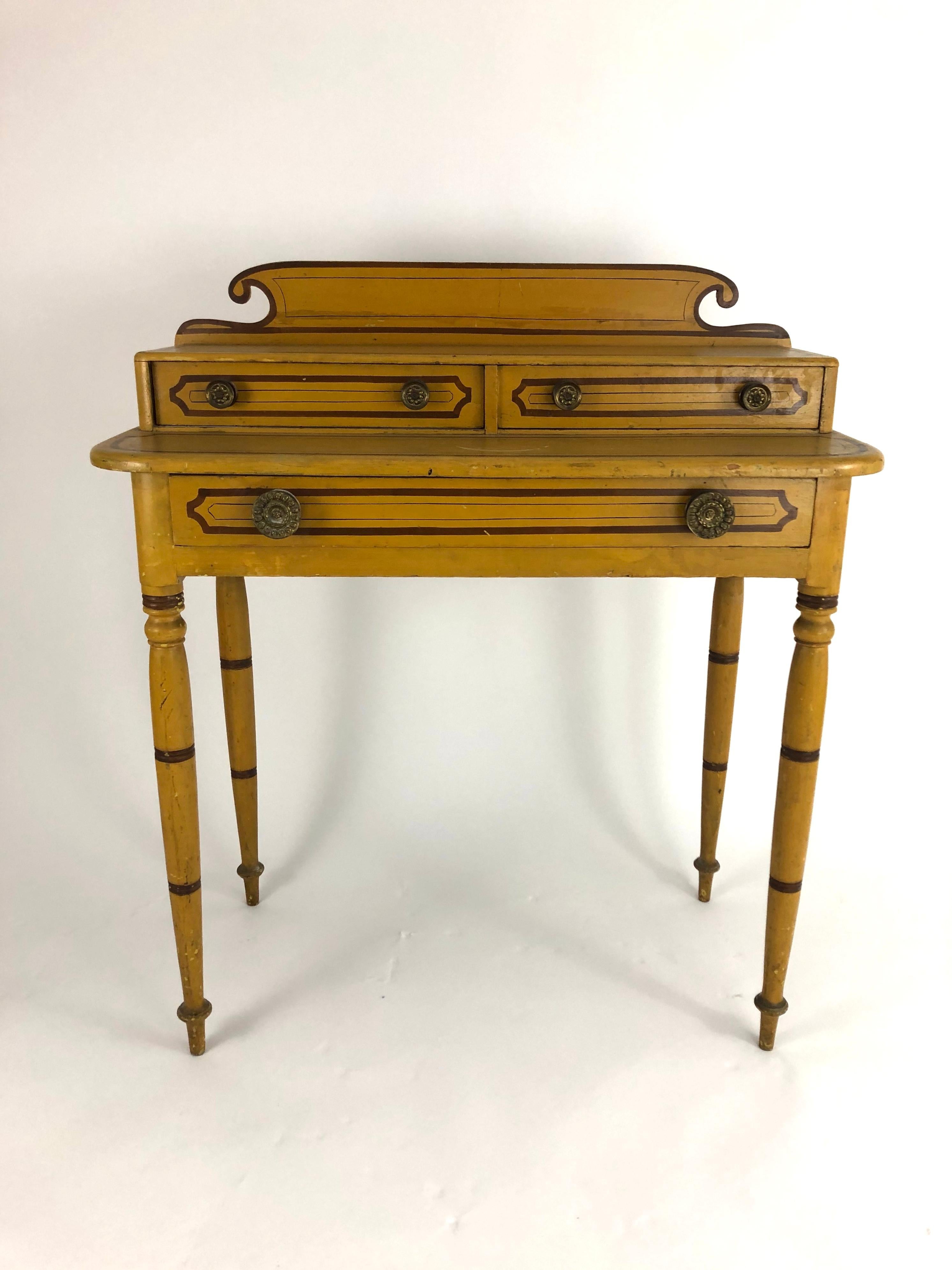 A 19th century American Country yellow painted pine dressing table, retaining its original painted decoration, with scrolled back splash over a superstructure containing two drawers above the tabletop with one long frieze drawer below, all supported