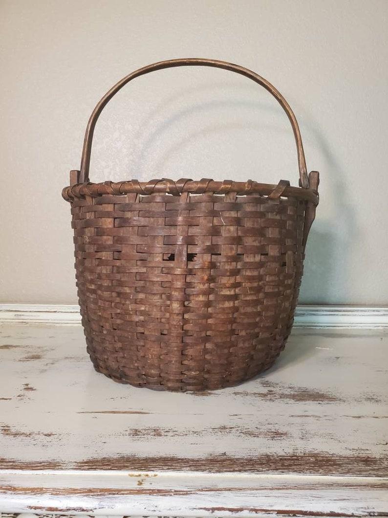 A beautiful large American stave woven splint basket from the 19th century, with a double rolled rim and a single swinging bentwood handle, attributed to G.W. Adams

Gathering baskets like this were used to gather fruits, vegetables, flowers, and
