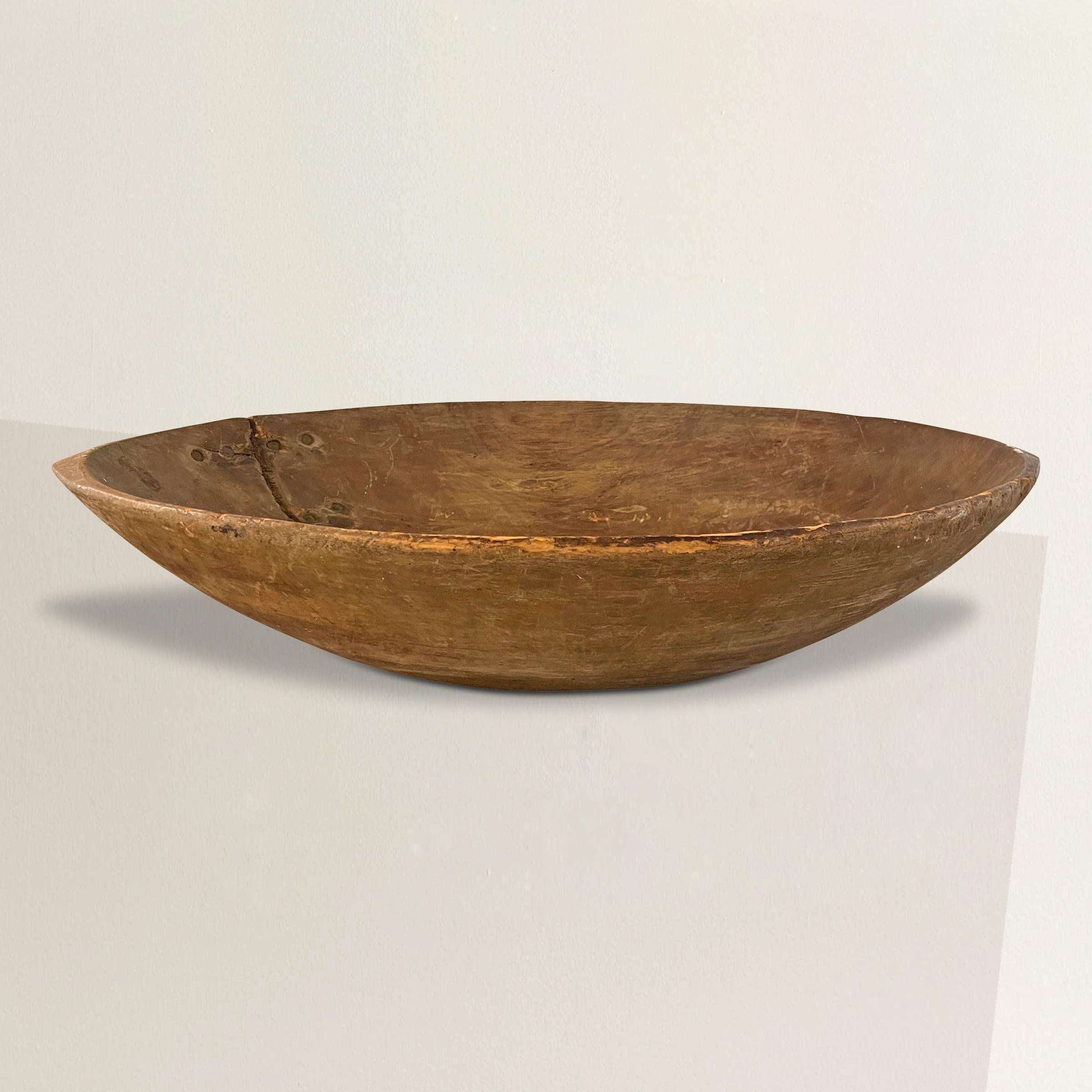 A wonderful large 19th century American carved wood dough bowl with a wonderful shape, and an old iron repair. At some point in its lifetime, someone added a hanger on the back so it can be hung on a wall in your kitchen or dining room. We've left