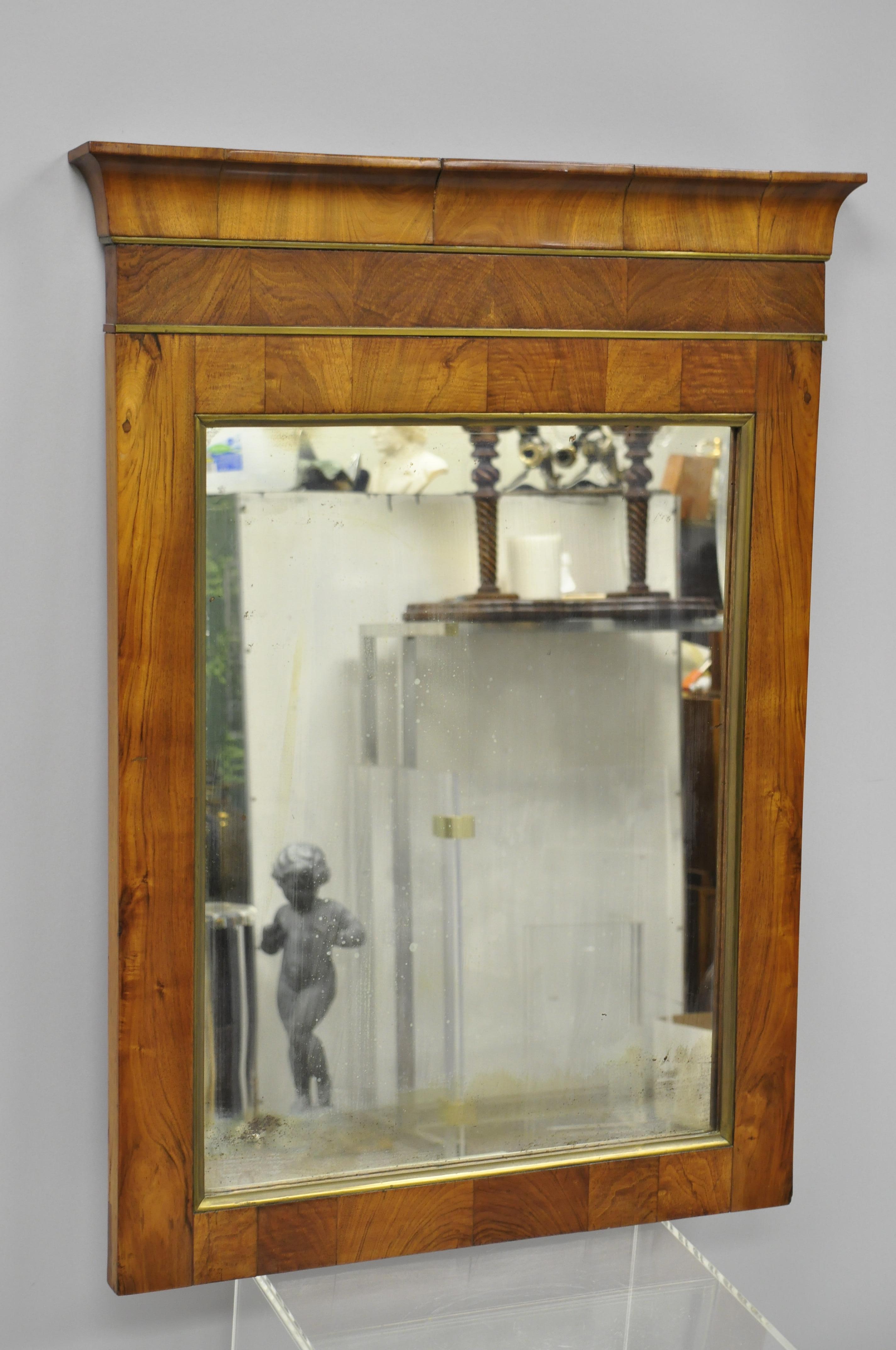 19th century American Empire crotch mahogany looking glass wall mirror with brass trim. Item features brass trim to crest and mirror border, and stunning crotch mahogany wood grain with 