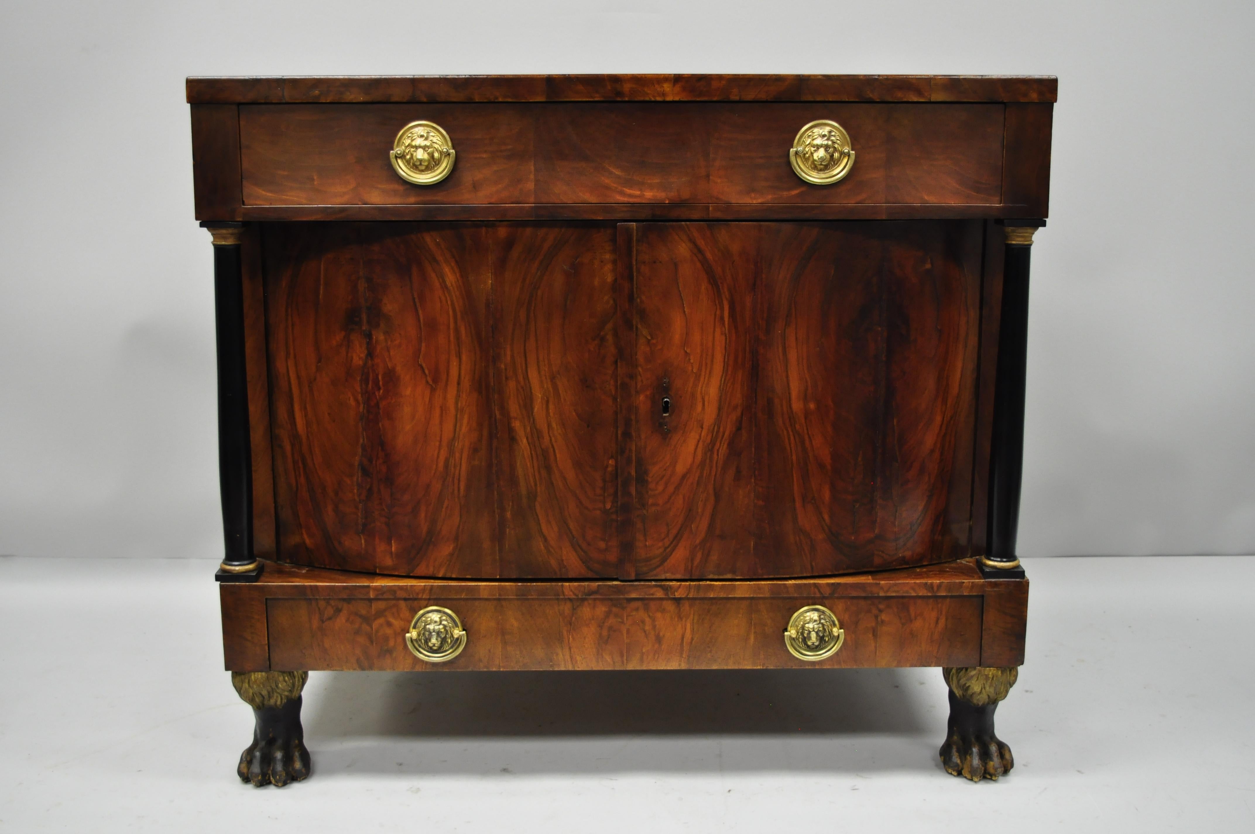 19th century American Empire lion claw foot crotch mahogany cabinet. Item features hairy claw feet, black column supports with gold accents, bow front cabinet doors, faux lower drawer, single dovetailed drawer, professionally refinished at some
