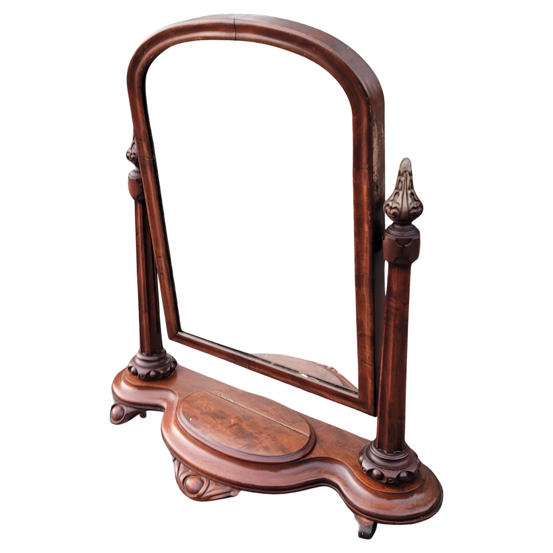 19th Century American Empire gentleman's tilt-top shaving mirror of mahogany. The original mirror glass is in a beveled frame with a dome top and is supported by beautifully crafter upright columns with spire finials. The serpentine shaped base is