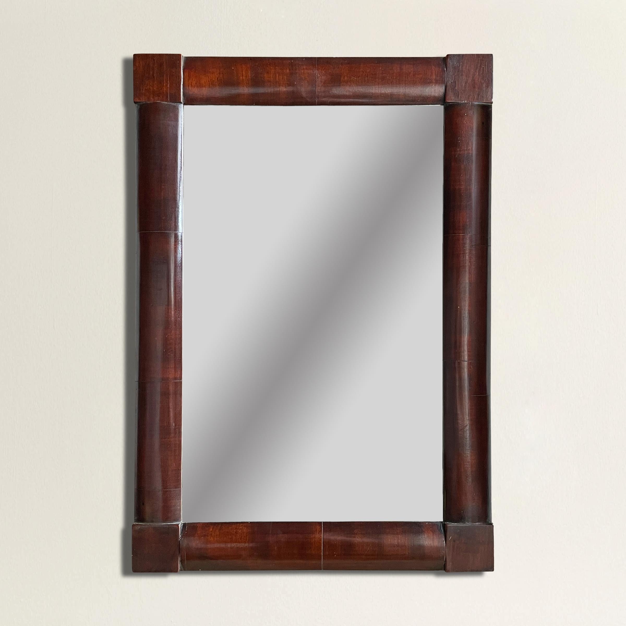 A petite 19th century American Empire mahogany veneer shaving mirror, and a rounded frame with square block corners.