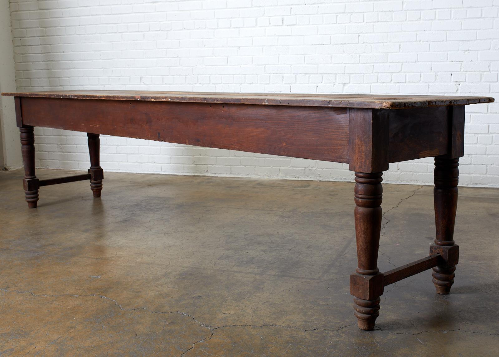 Large 19th century American farmhouse table, work table, or harvest table. Featuring a rustic plank top 10 feet long. Supported by thick turned legs conjoined with a stretcher. Makes a wonderful display table or console table. Very heavy and solid