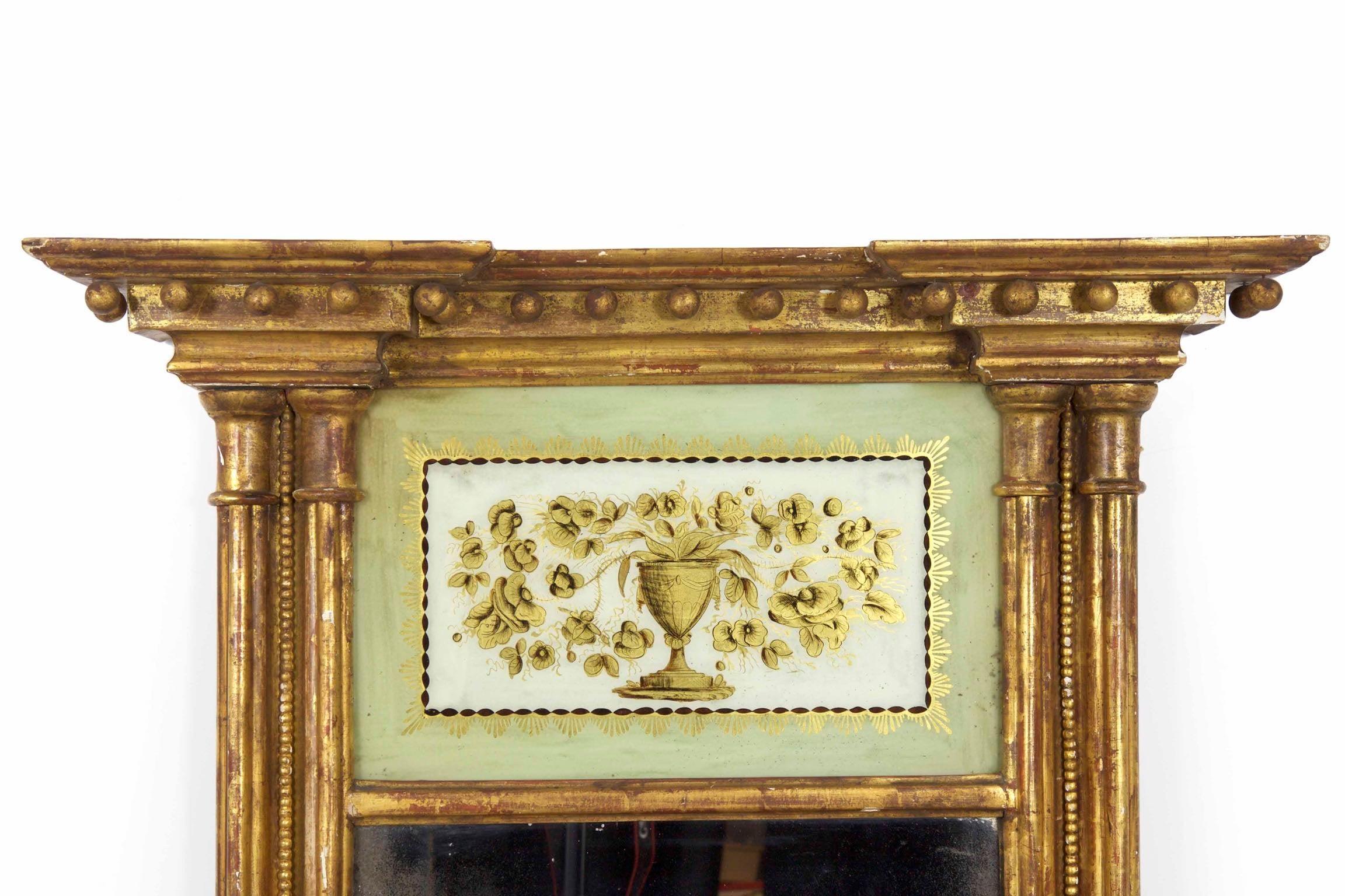 An inordinately fine and powerful presentation, this Federal period giltwood mirror is designed as an architectural representation of the home it would generally hang in. From the bold projecting crest molding hang a series of giltwood spheres