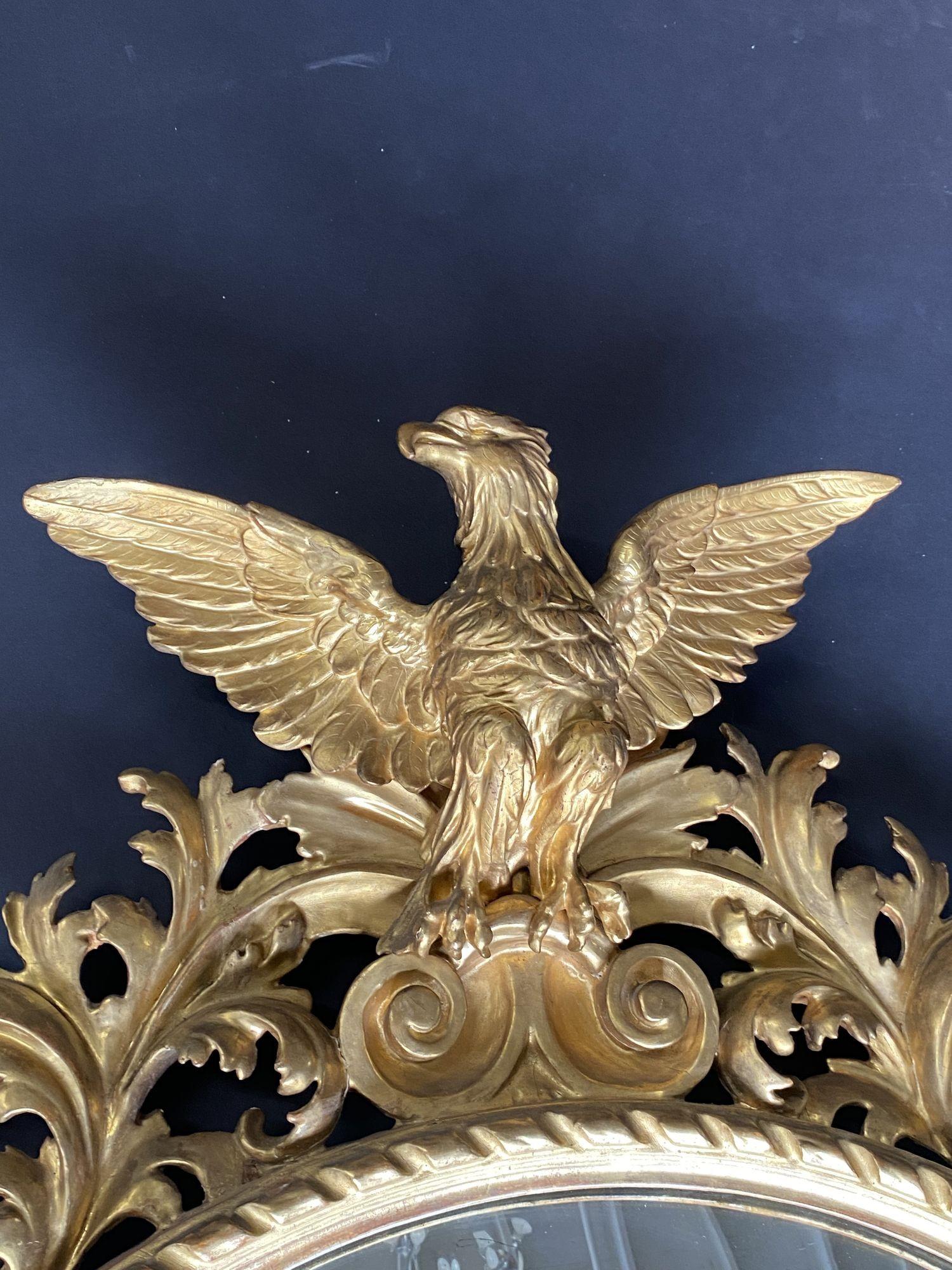 Miroir fédéral américain du 19ème siècle, grand aigle à œil de bœuf. Bois sculpté et doré, corps entier, aile déployée, aigle, cadre à volutes feuillagées, décor inférieur de coquilles.