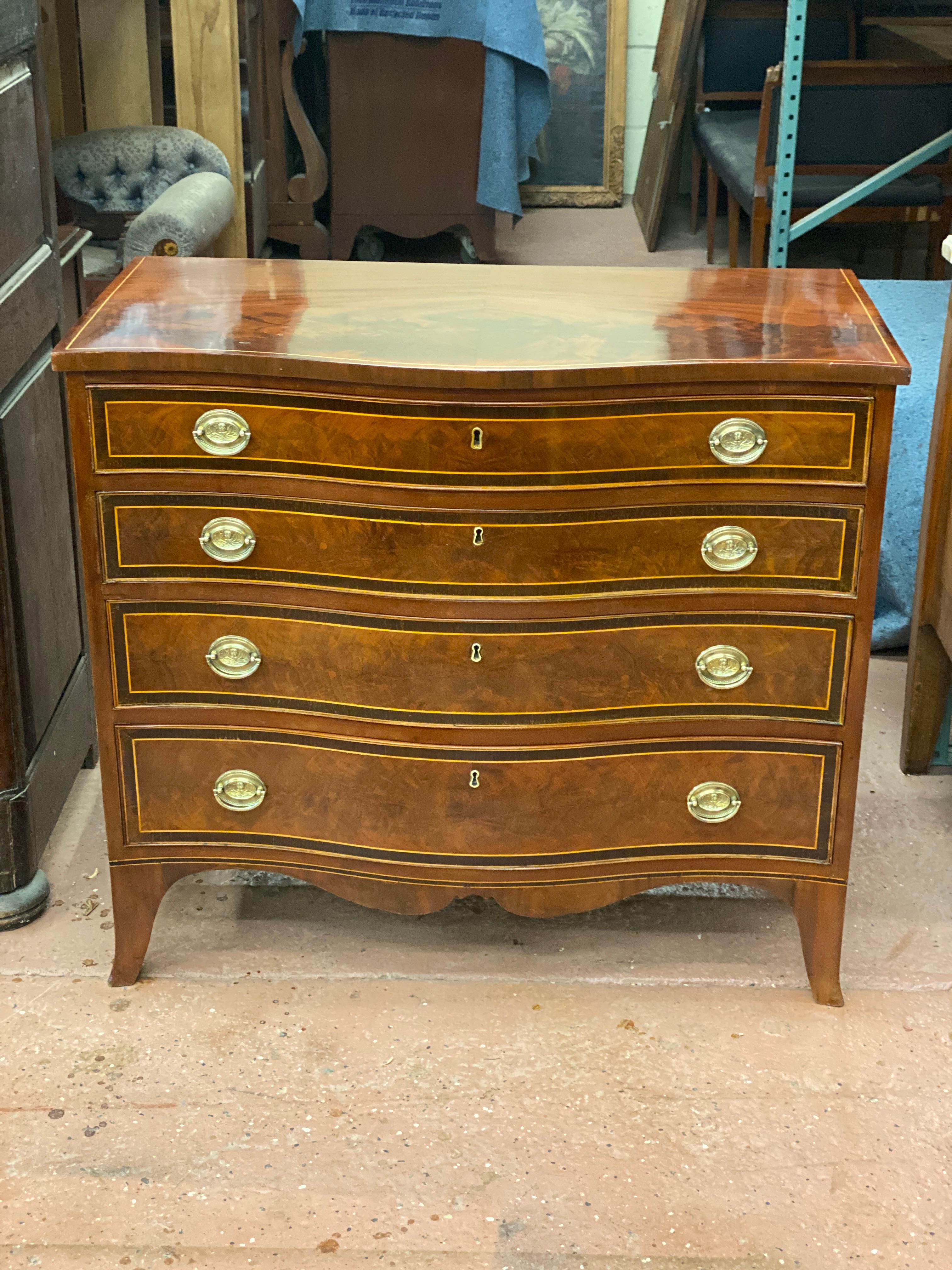 Handsome early to mid 19th century Serpentine front chest with four graduated drawers The drawer fronts are banded with rosewood and satinwood veneer. The brass bail pulls are decorated with rosettes. The top is highly French polished crotched