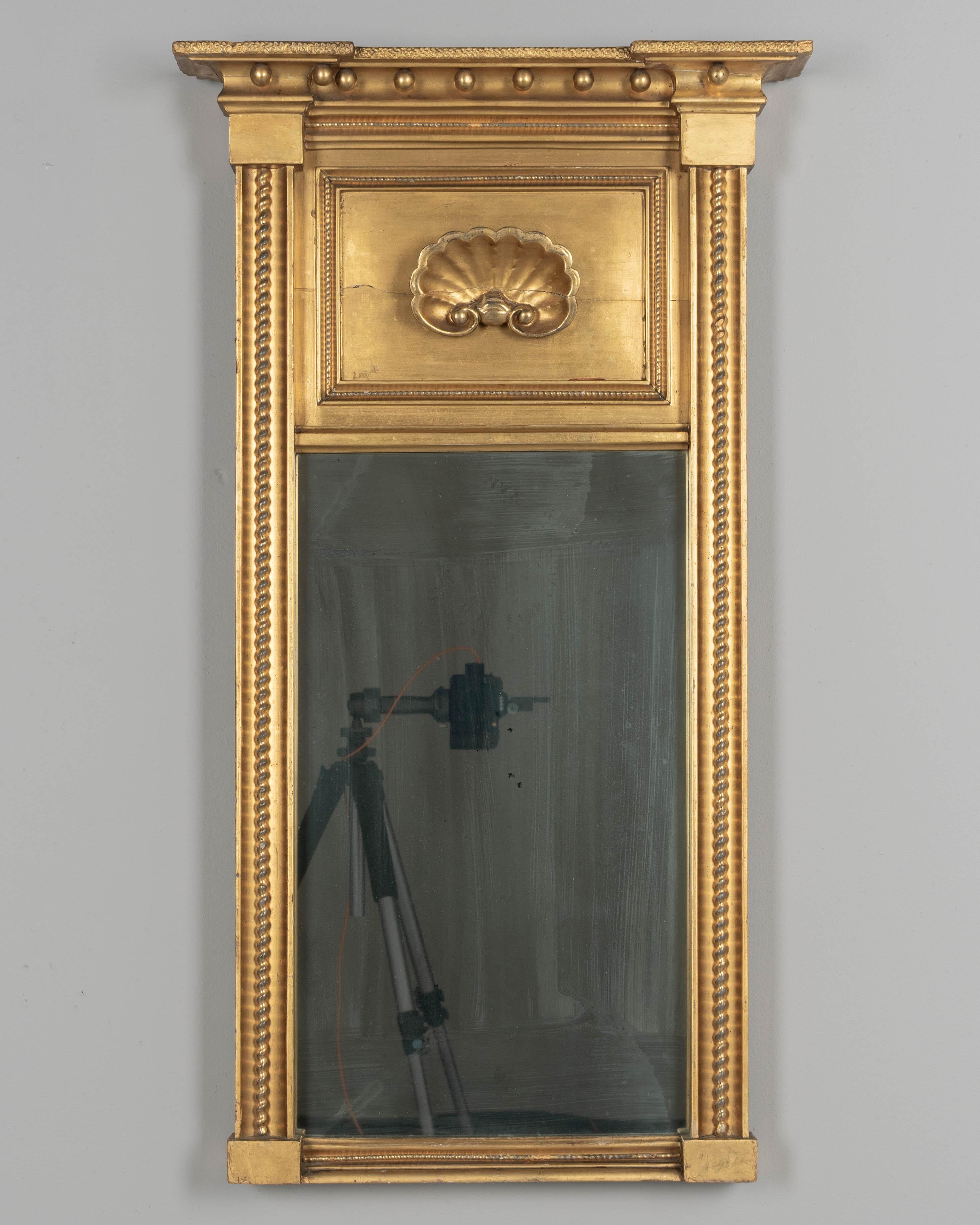 Specchio da molo in legno dorato in stile Feder del XIX secolo con pannello centrale intagliato a conchiglia, corona architettonica con sfere dorate e modanatura a corda lungo i lati. Lo specchio originale presenta una patina striata. Restauro su