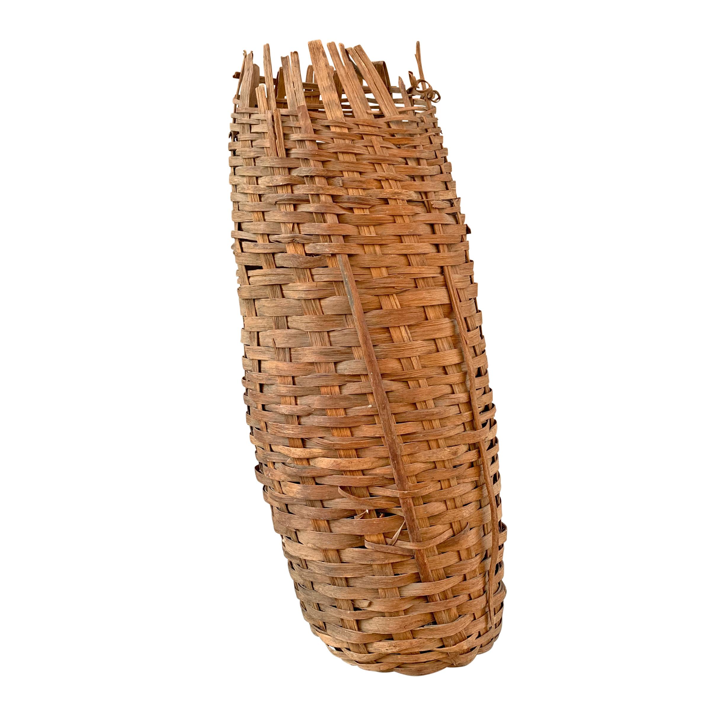 A fantastic sculptural 19th century American oak splint fishing basket of cylindrical form with one end turned in on itself. Basket stands up vertically, but would also be interesting hung horizontally on a wall.