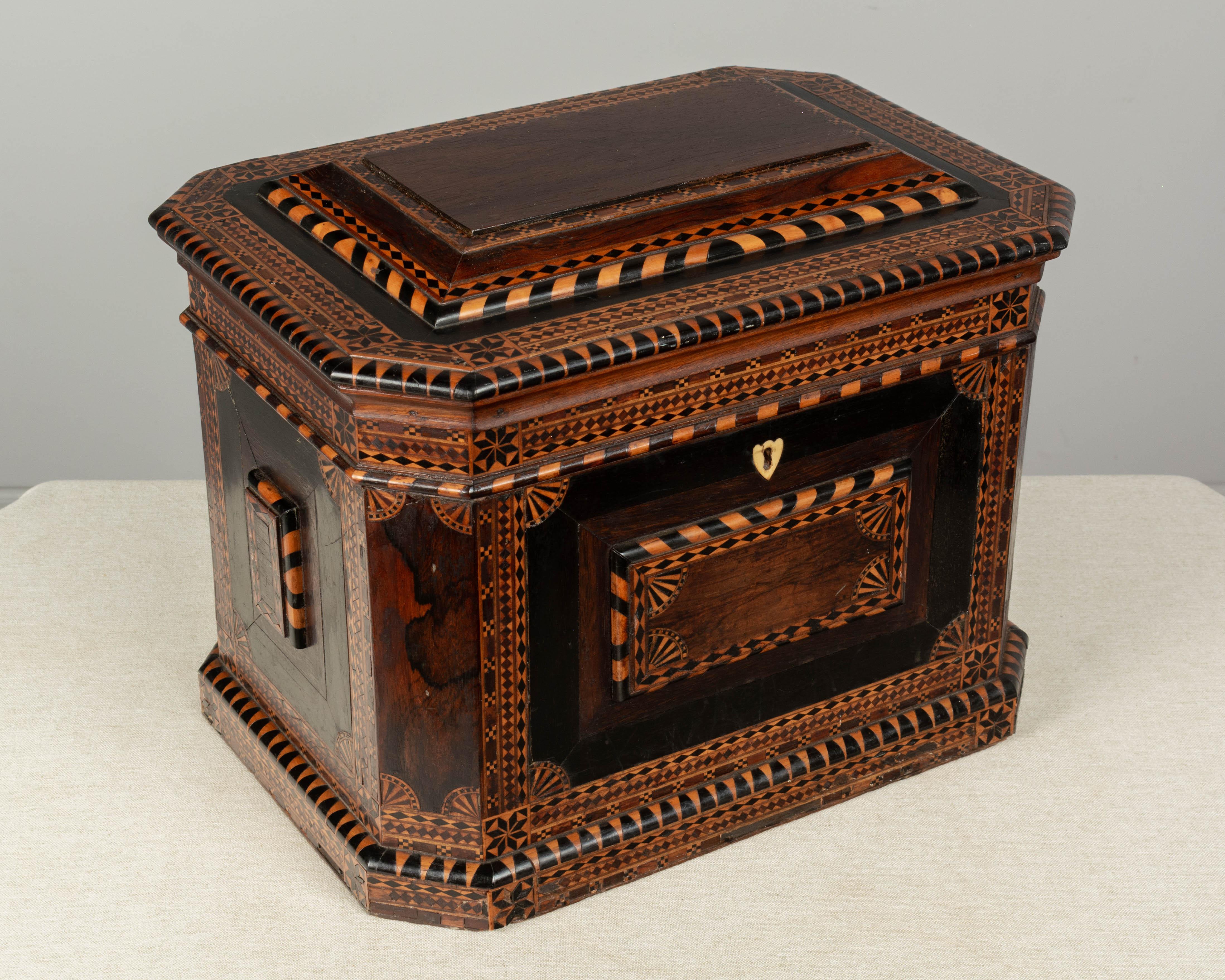 A large 19th century American folk art marquetry box made of rosewood with various inlaid wood veneers and ebonized decoration. This was probably a sewing box and was made by a skilled craftsman who used some of the geometric motifs common in