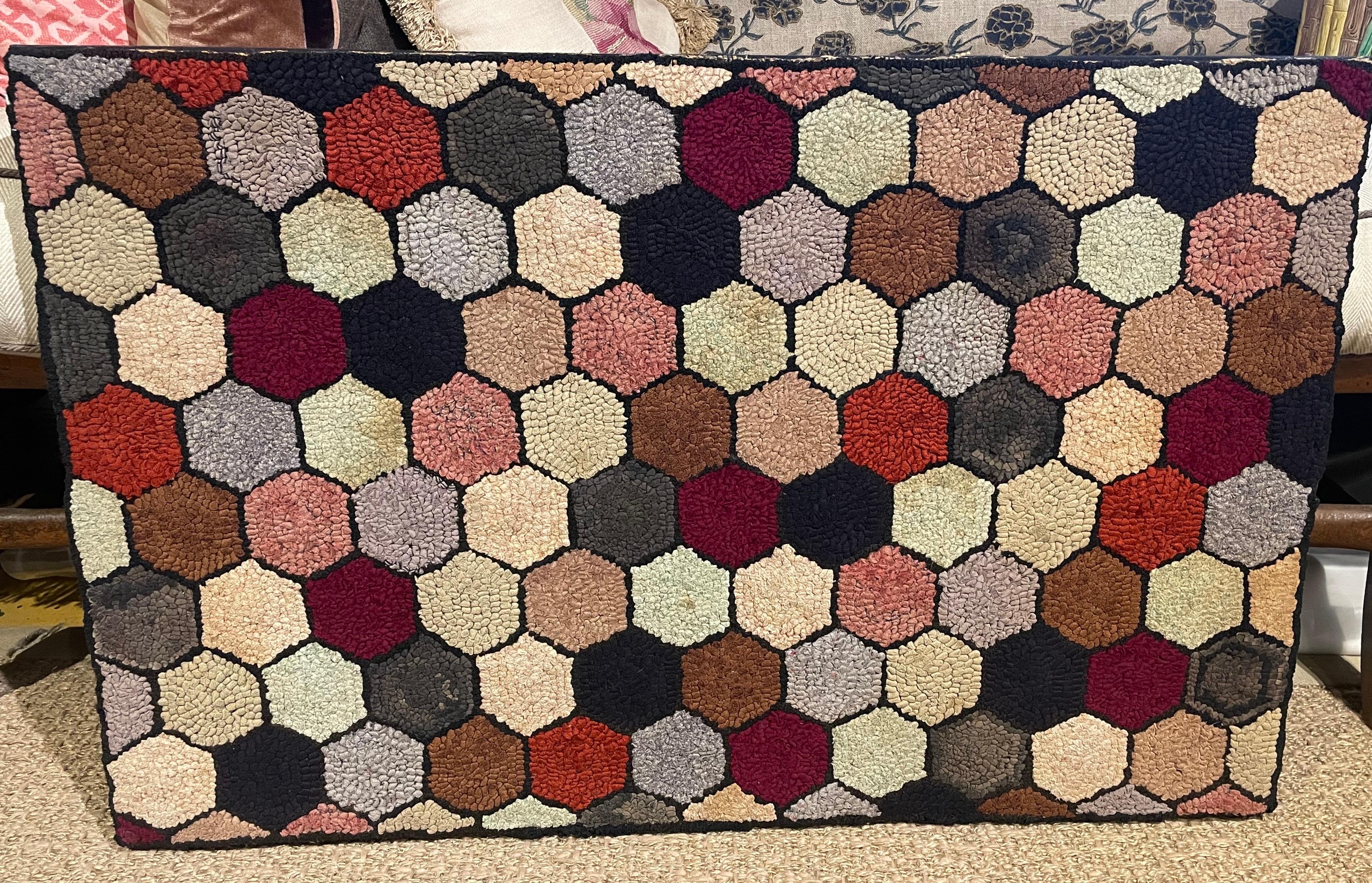 Vibrant antique hooked rug composed of numerous hexagons of various colors, all surrounded by black borders. Professionally backed with burlap and mounted on black linen wrapped wood stretcher with foam core backing. Wired to be hung either