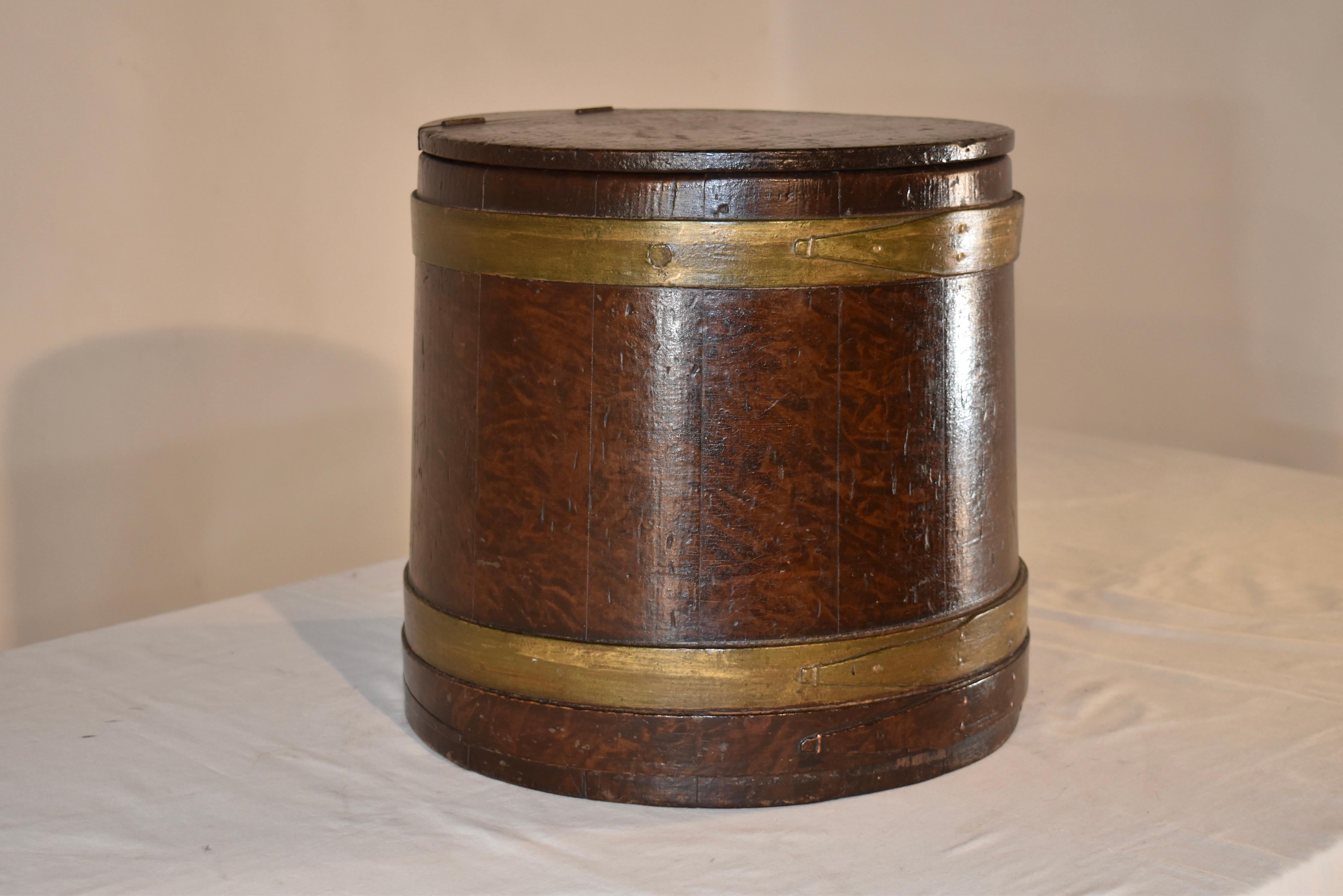 19th century American lidded box.  The box is circular and is grain painted to look like burl wood.  The box is banded with wrapped wooden straps, hand painted in god to have the look of brass.  The box has a hinged lid which lifts to reveal